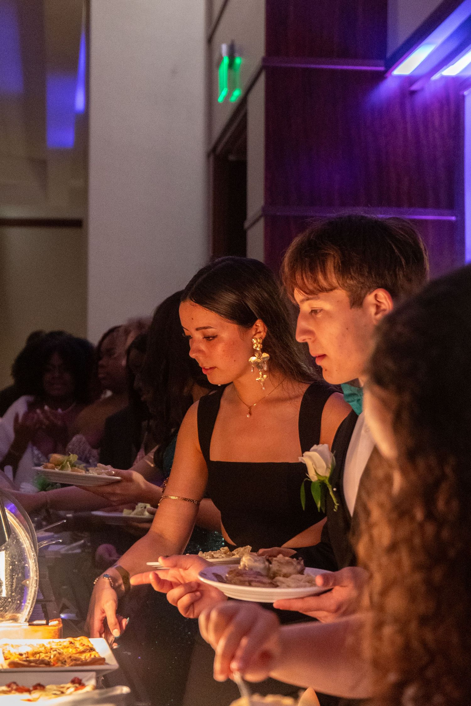 Dimly lit dinner event with purple accent lighting shows guests dining at tables.