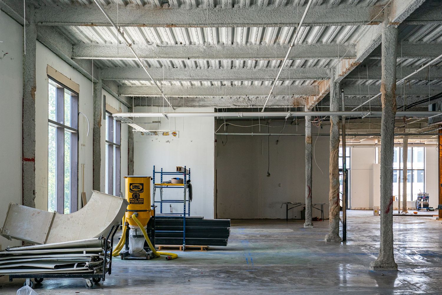 Spacious commercial interior with metal ceiling structure and concrete floor.