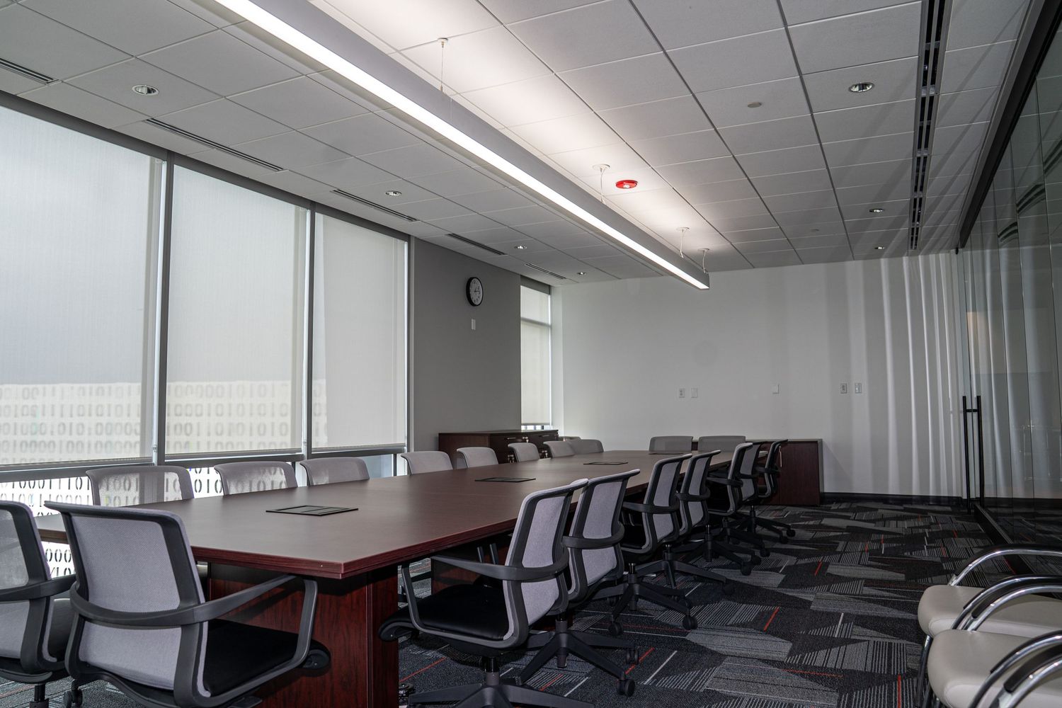 Modern office conference room with glass walls and multiple office chairs.