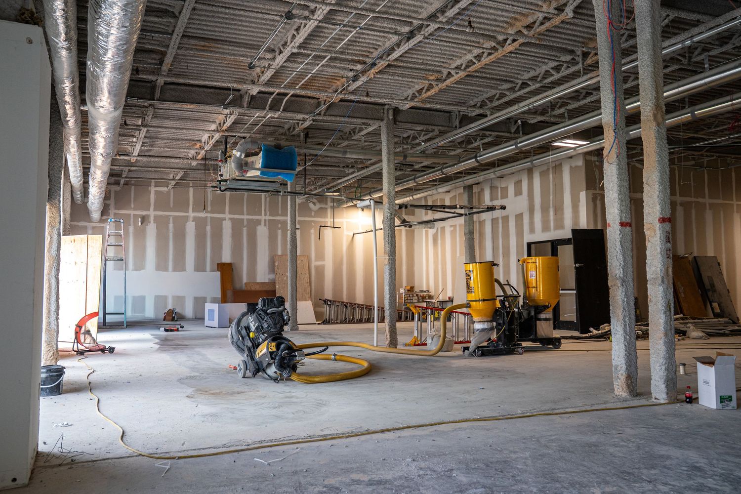 Large open warehouse space under construction with support columns and exposed mechanical systems.