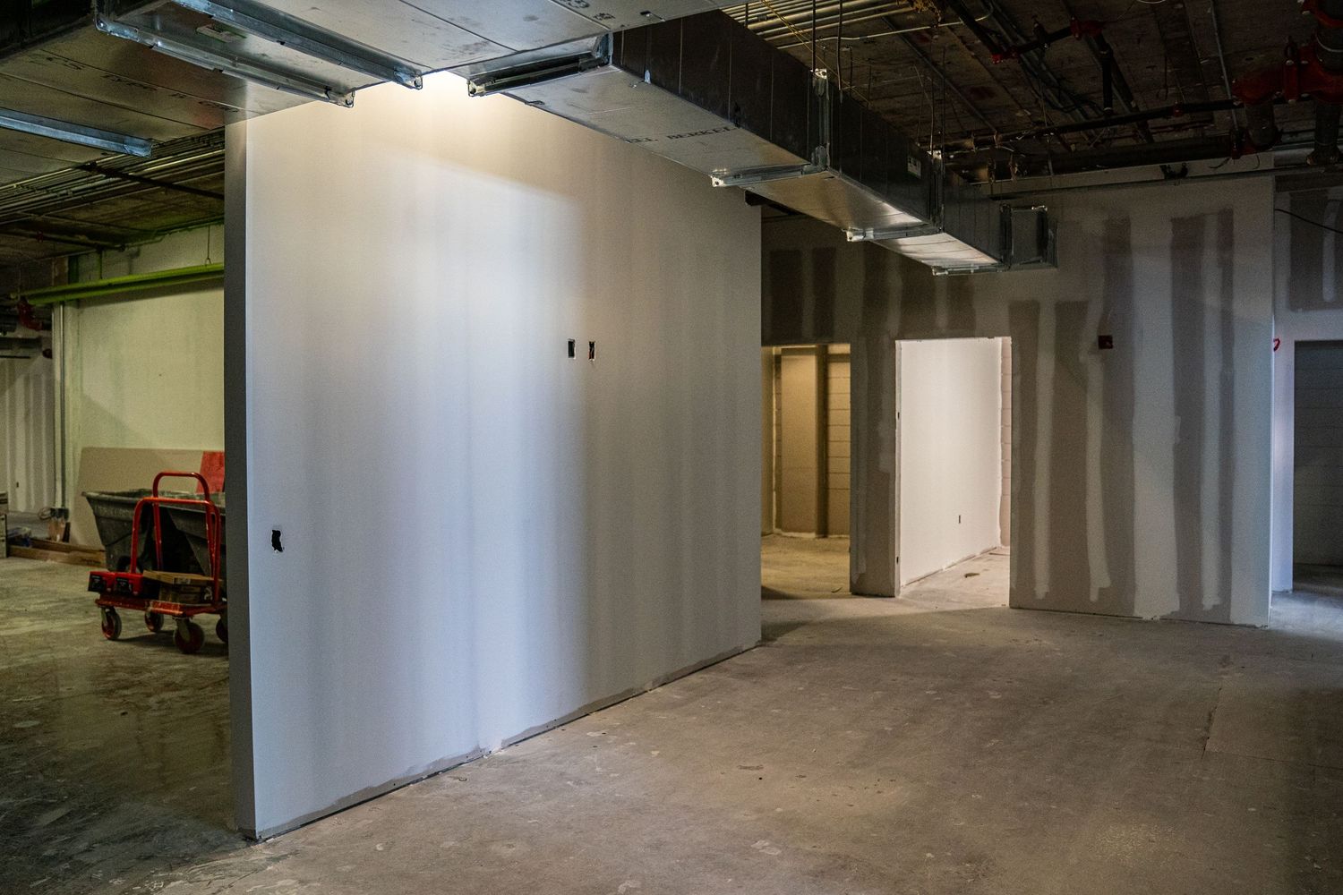 White-walled commercial space under construction with exposed ceiling infrastructure.