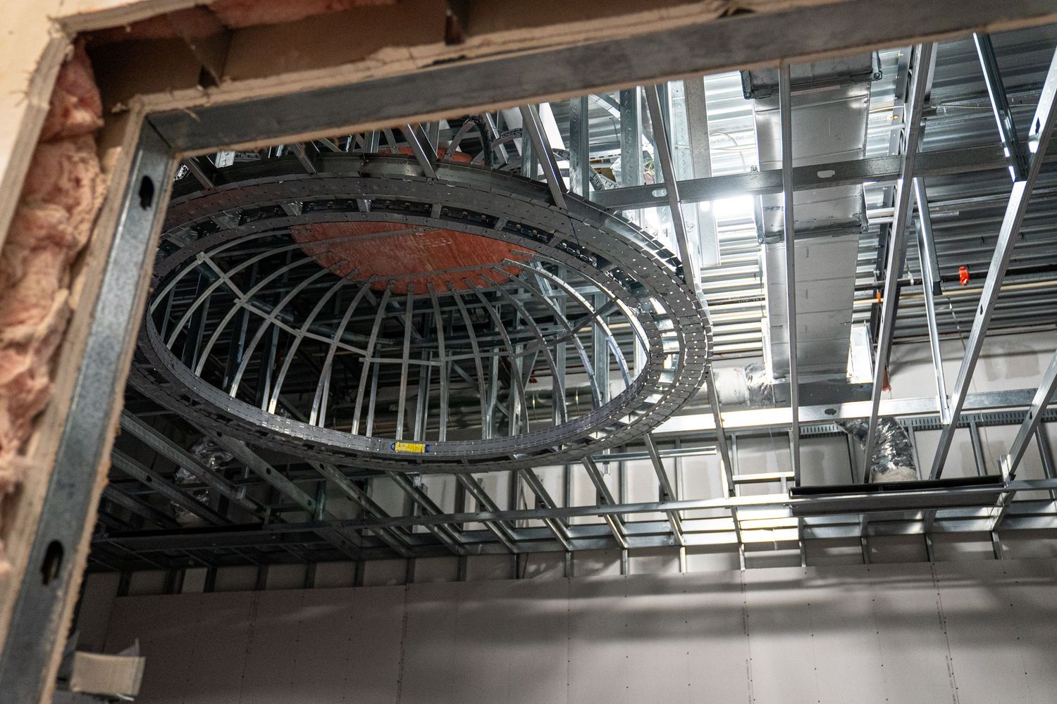 A circular metal framework in an unfinished ceiling reveals industrial construction details and ductwork.