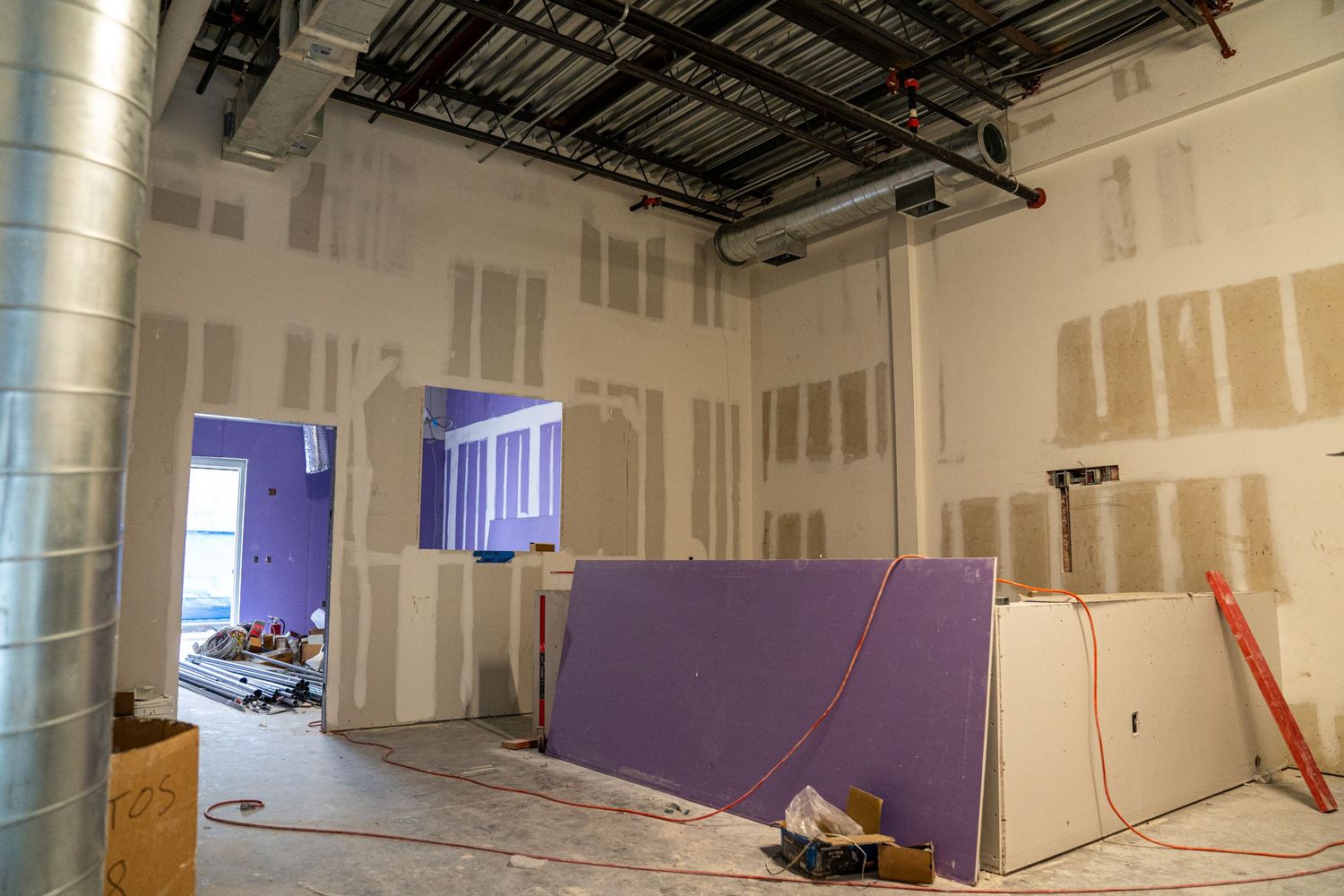 Construction site interior with purple temporary wall and blue-lit doorway visible.