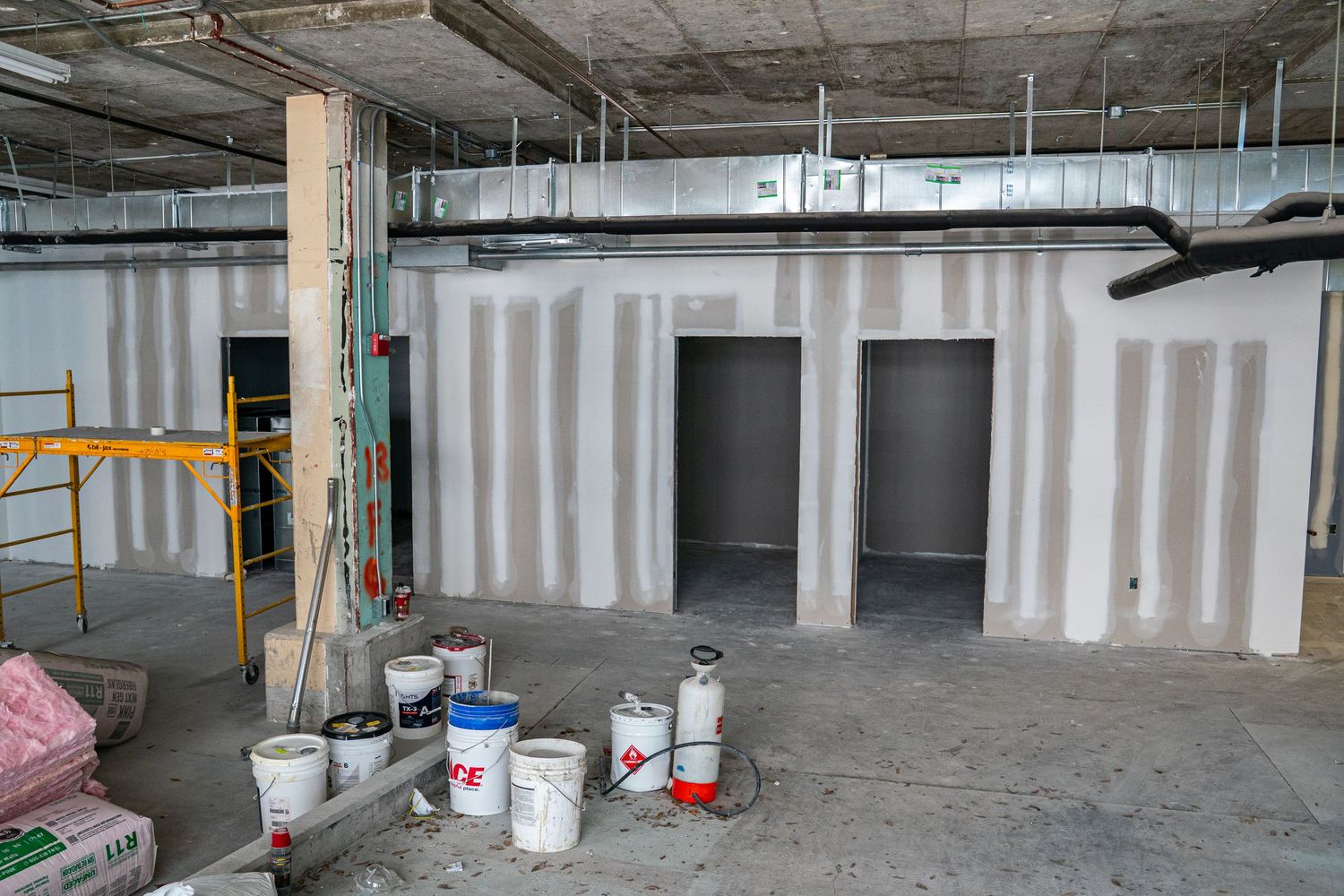 Unfinished commercial space with exposed ceiling and concrete floors during renovation.