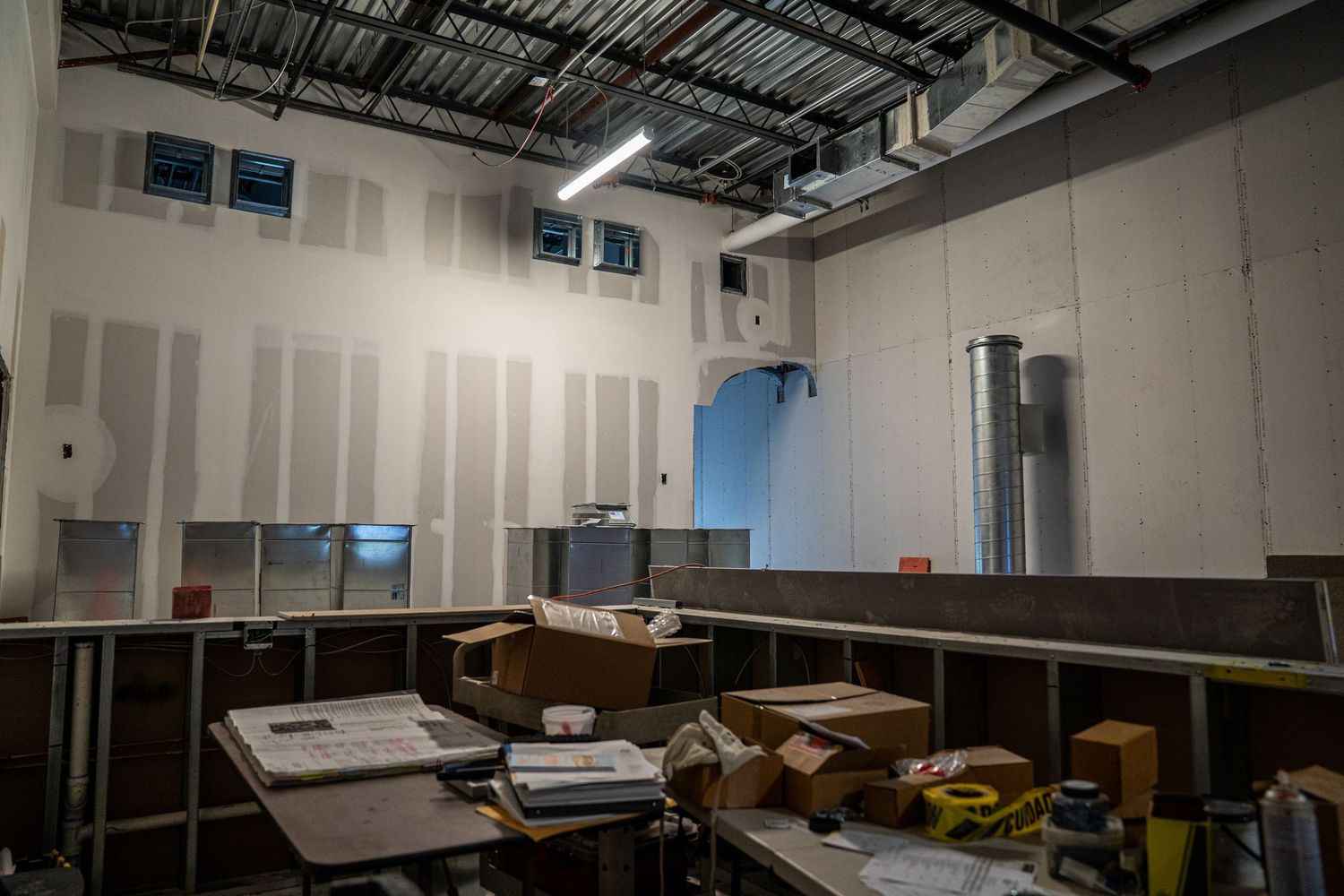 Large open commercial space during renovation with exposed mechanical systems overhead.