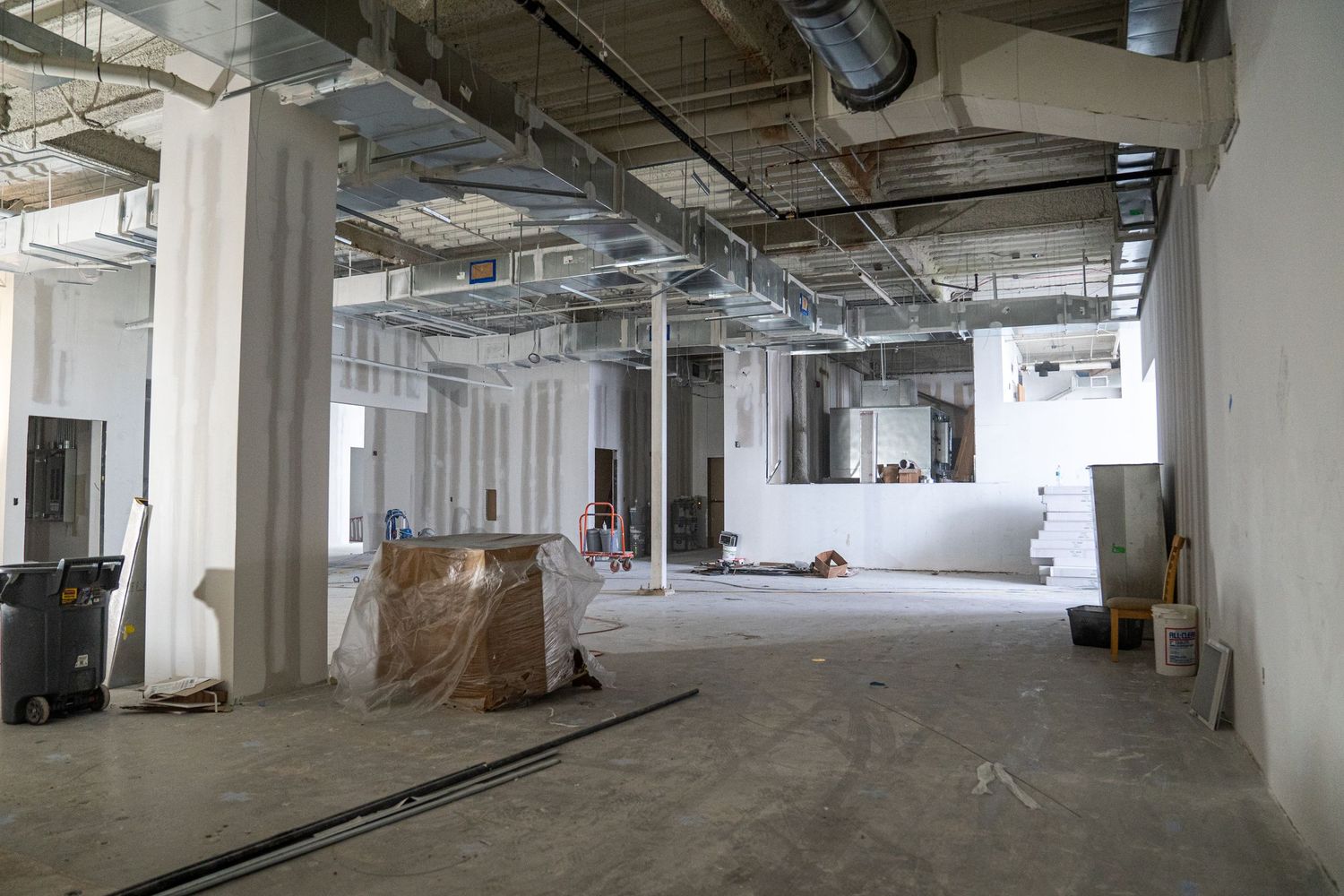 Spacious commercial interior under renovation with industrial ceiling and support columns.