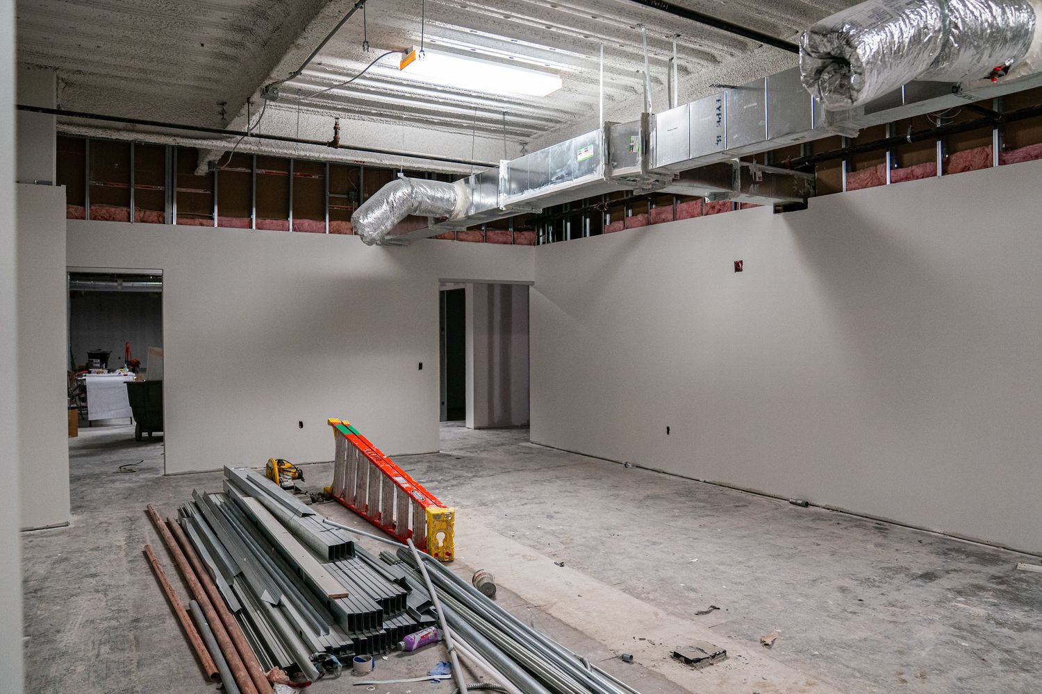 Wide angle view of commercial space renovation showing ductwork and unfinished walls.