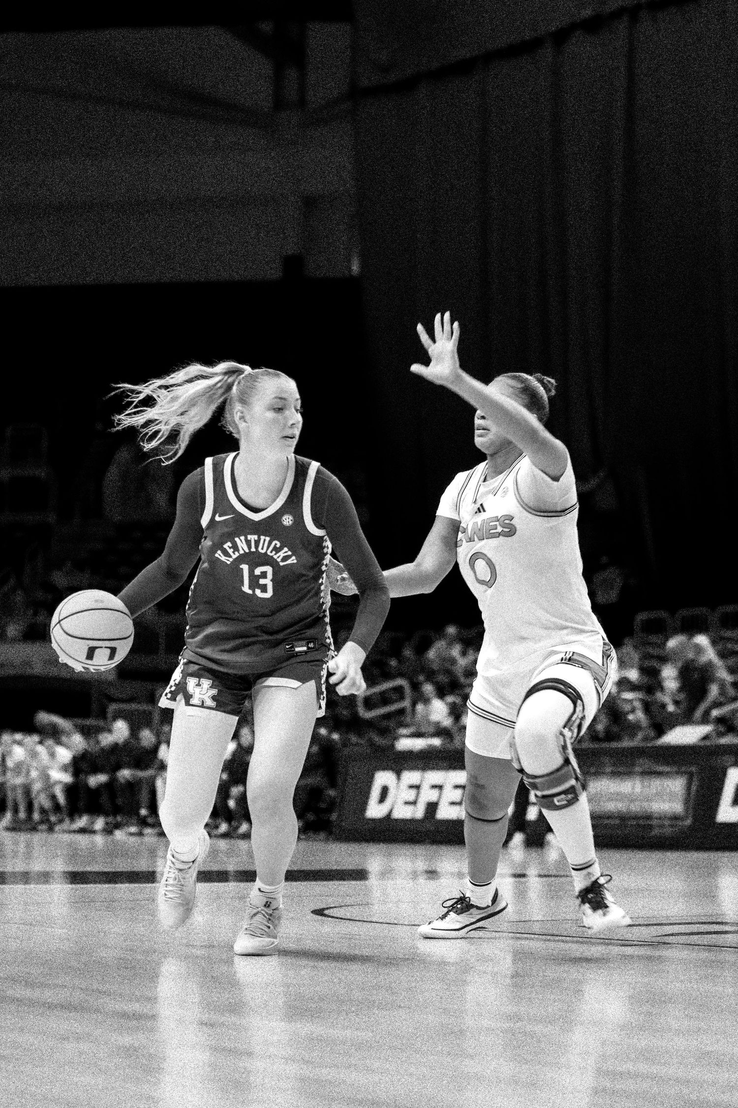 Basketball players compete for possession on hardwood court in black and white photo.