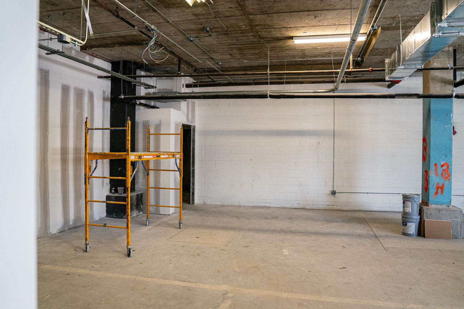 Construction area with yellow scaffolding and exposed industrial ceiling.