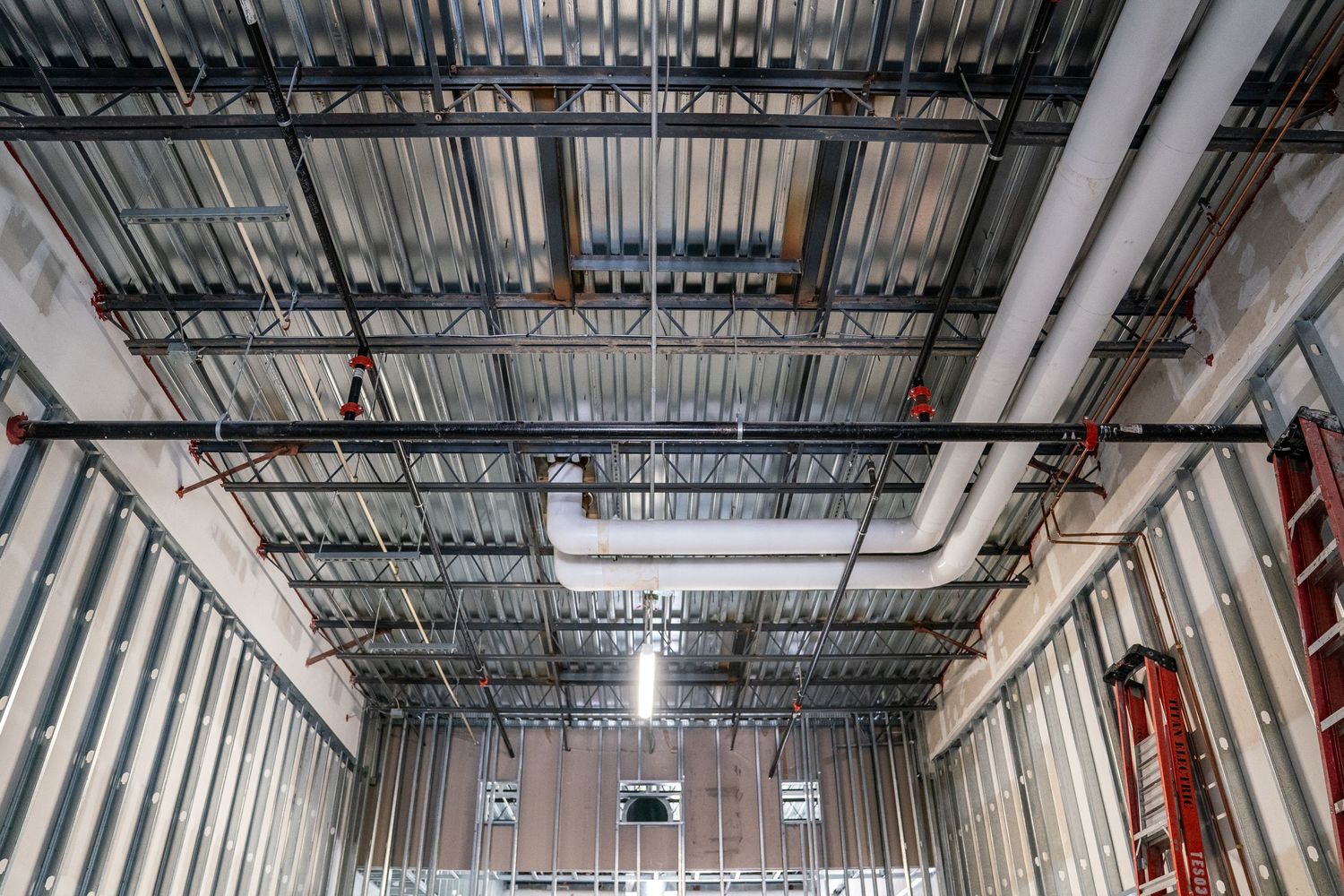 Wide angle view of building interior showing metal framing and mechanical systems installation.