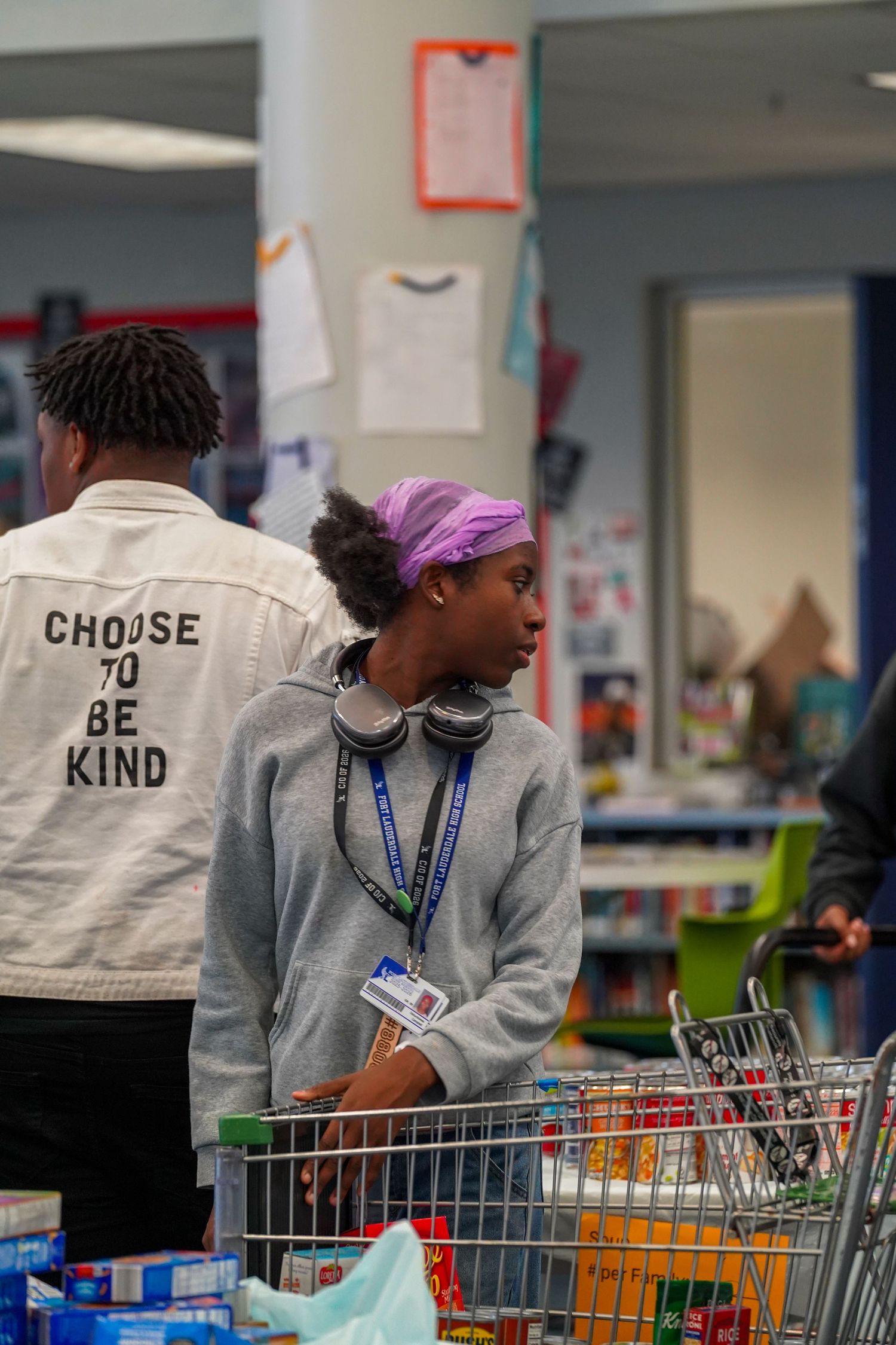 Shopping carts in store with person wearing white jacket that says 'Choose Be Kind'.