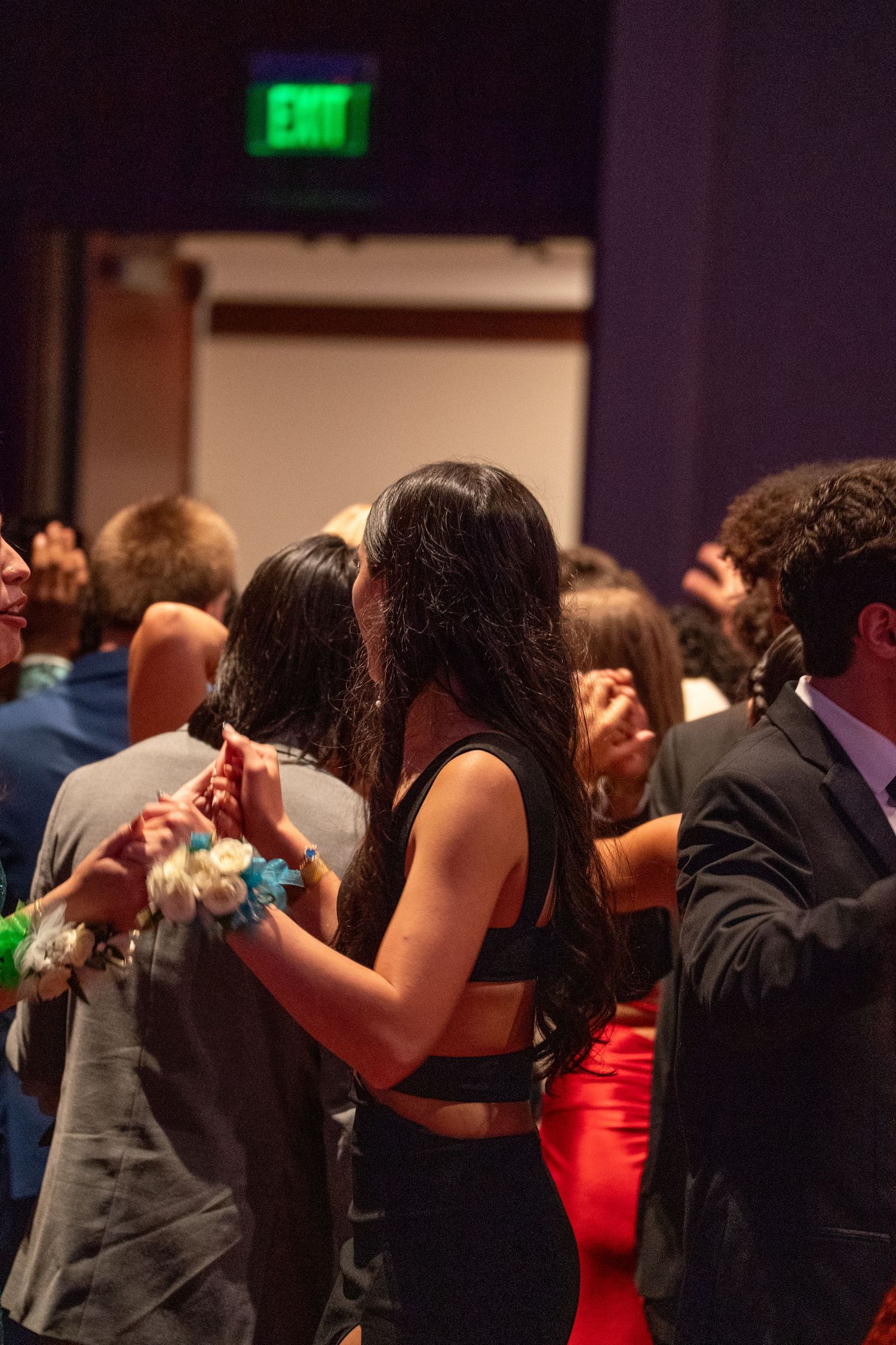 Couples dancing together at an indoor social event with colorful lighting.