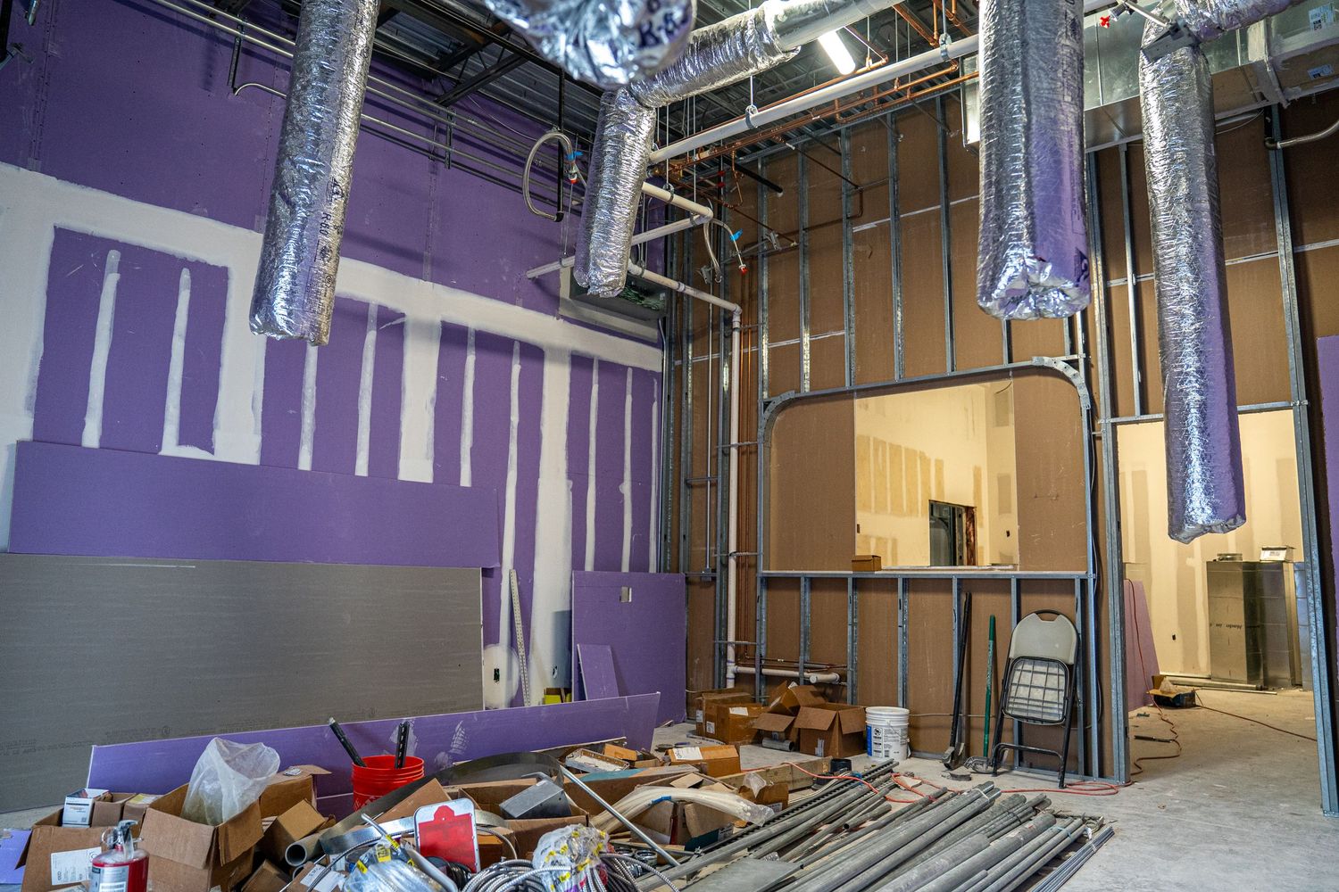Industrial space with purple accent walls showing renovation progress and exposed ductwork.