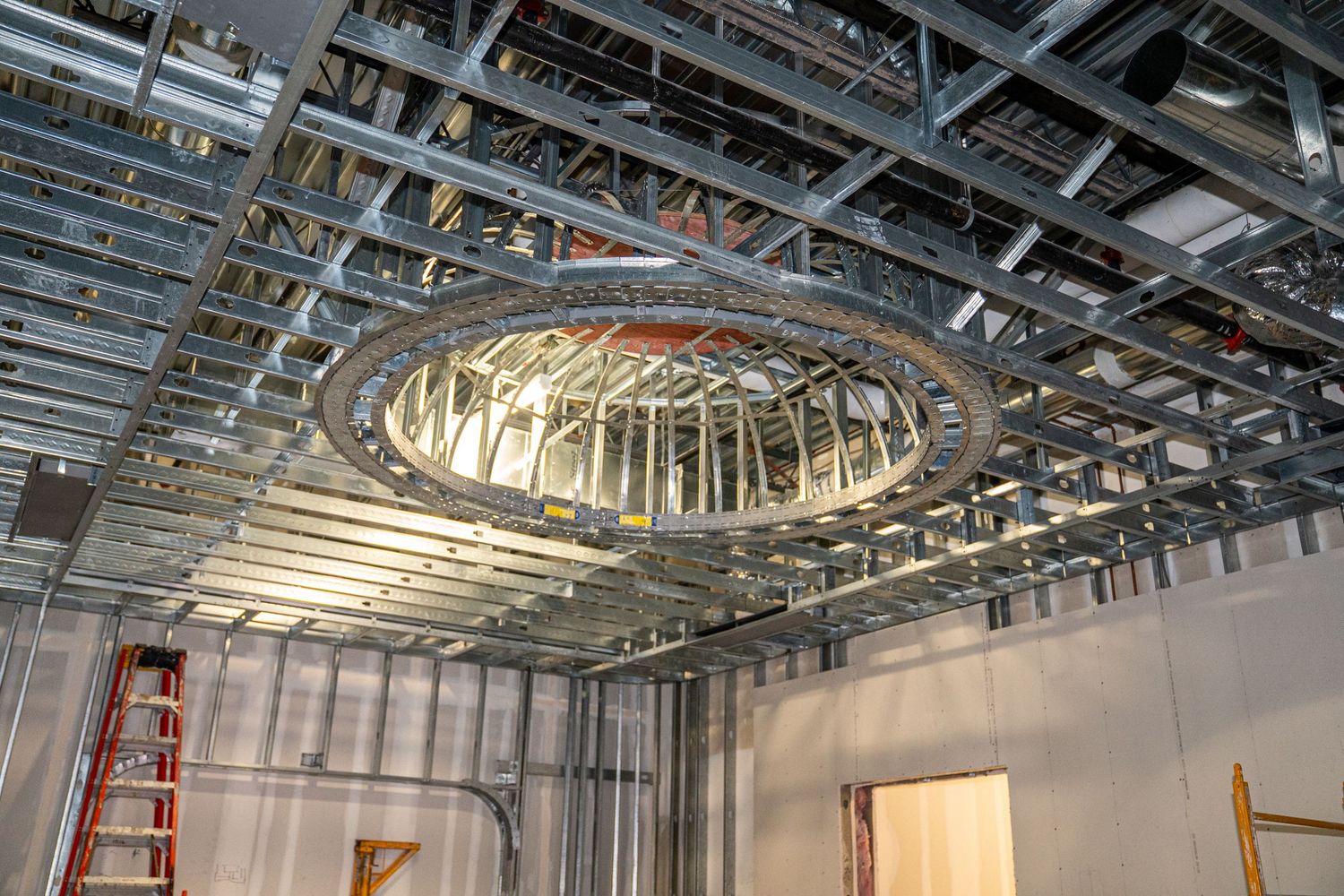 Industrial ceiling infrastructure with metal framing and ductwork during construction phase.