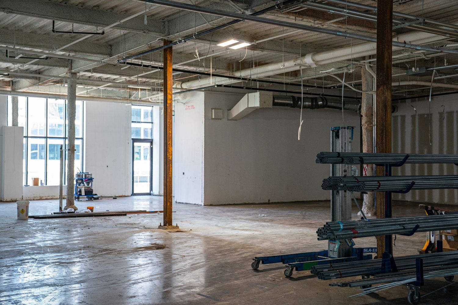 Empty commercial space under construction with exposed ceiling and support columns.