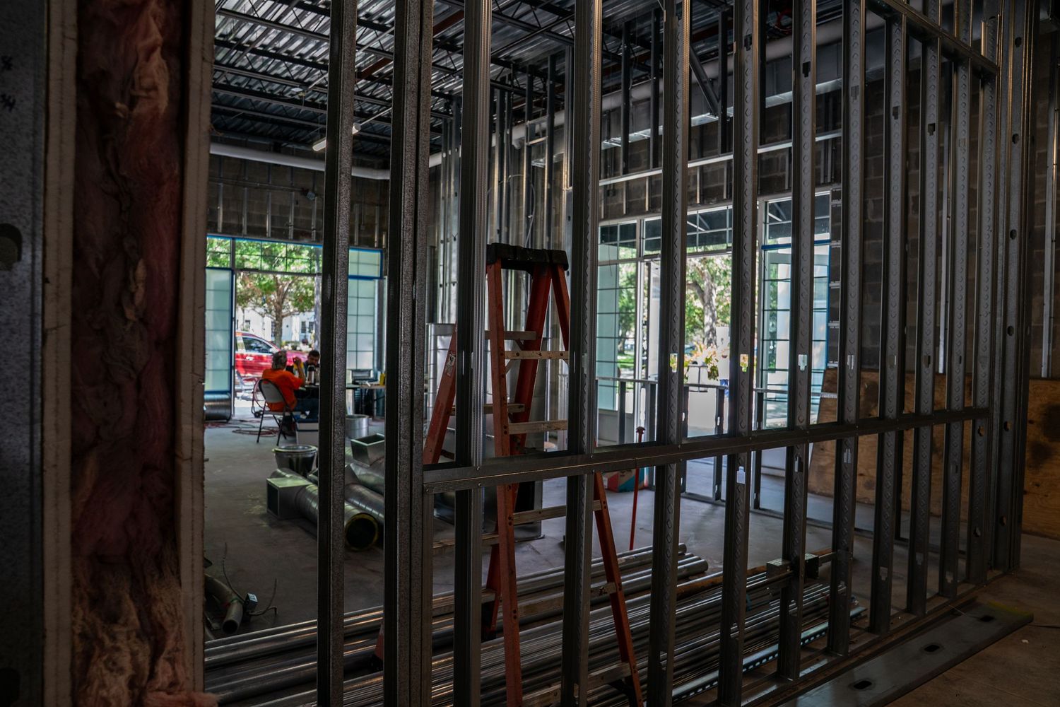 Commercial construction space with metal studs and exposed ceiling infrastructure during build-out phase.