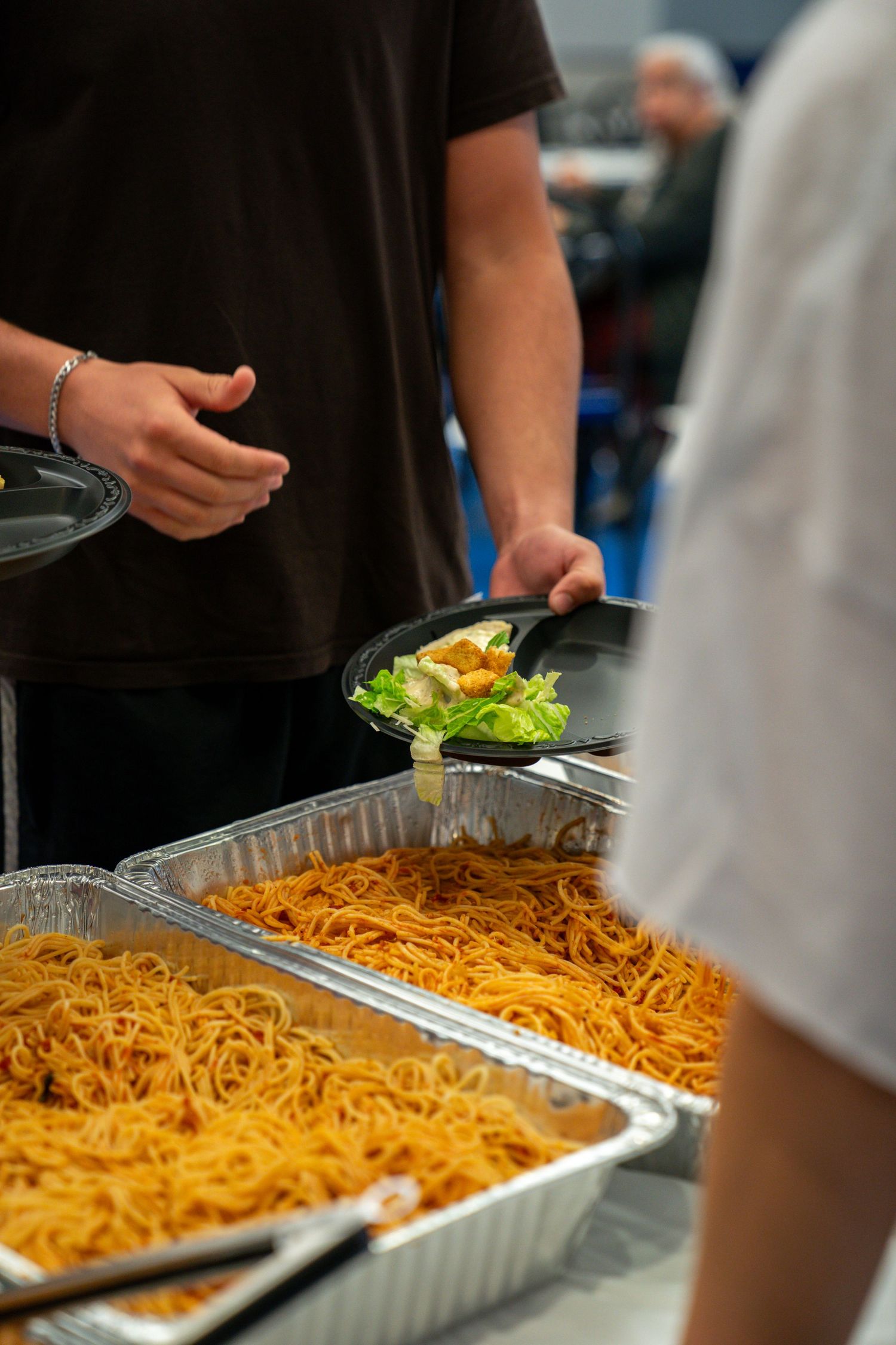 Large tray of spaghetti pasta being served at a buffet line.