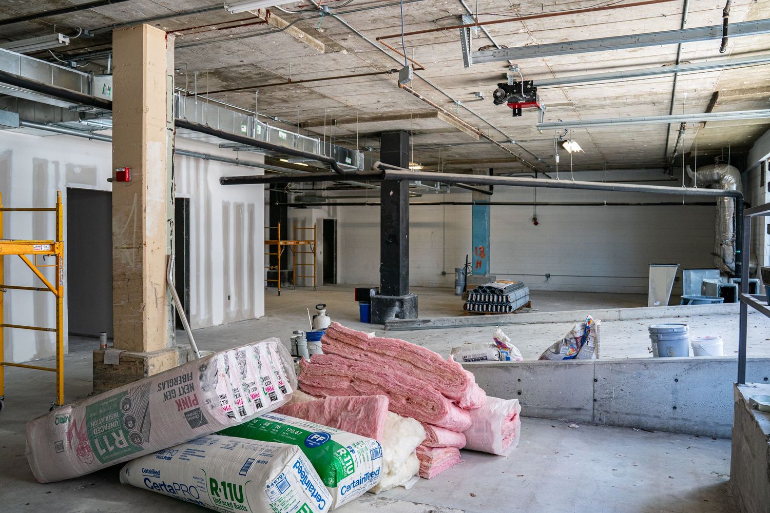 Unfinished commercial interior with construction materials and exposed building systems.
