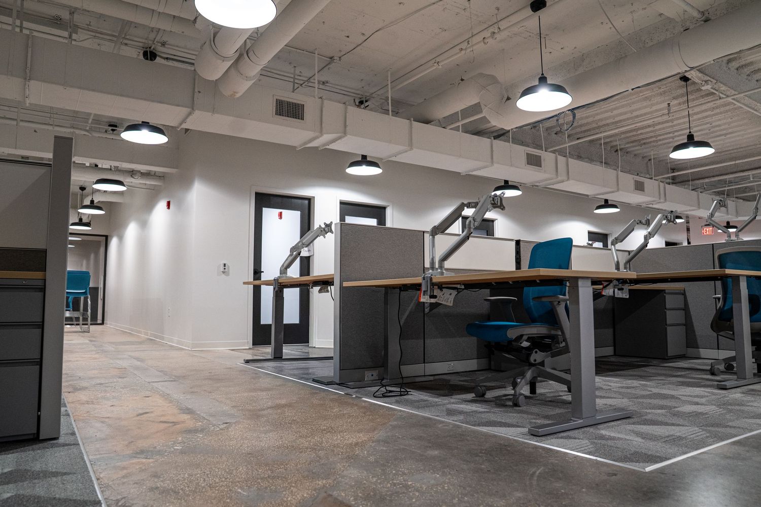 Spacious commercial interior under construction with pendant lighting and concrete floors.
