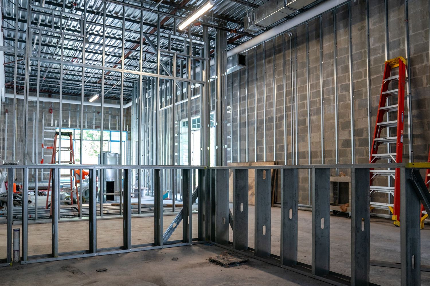 Wide view of commercial construction site with metal framing and exposed ceiling infrastructure.