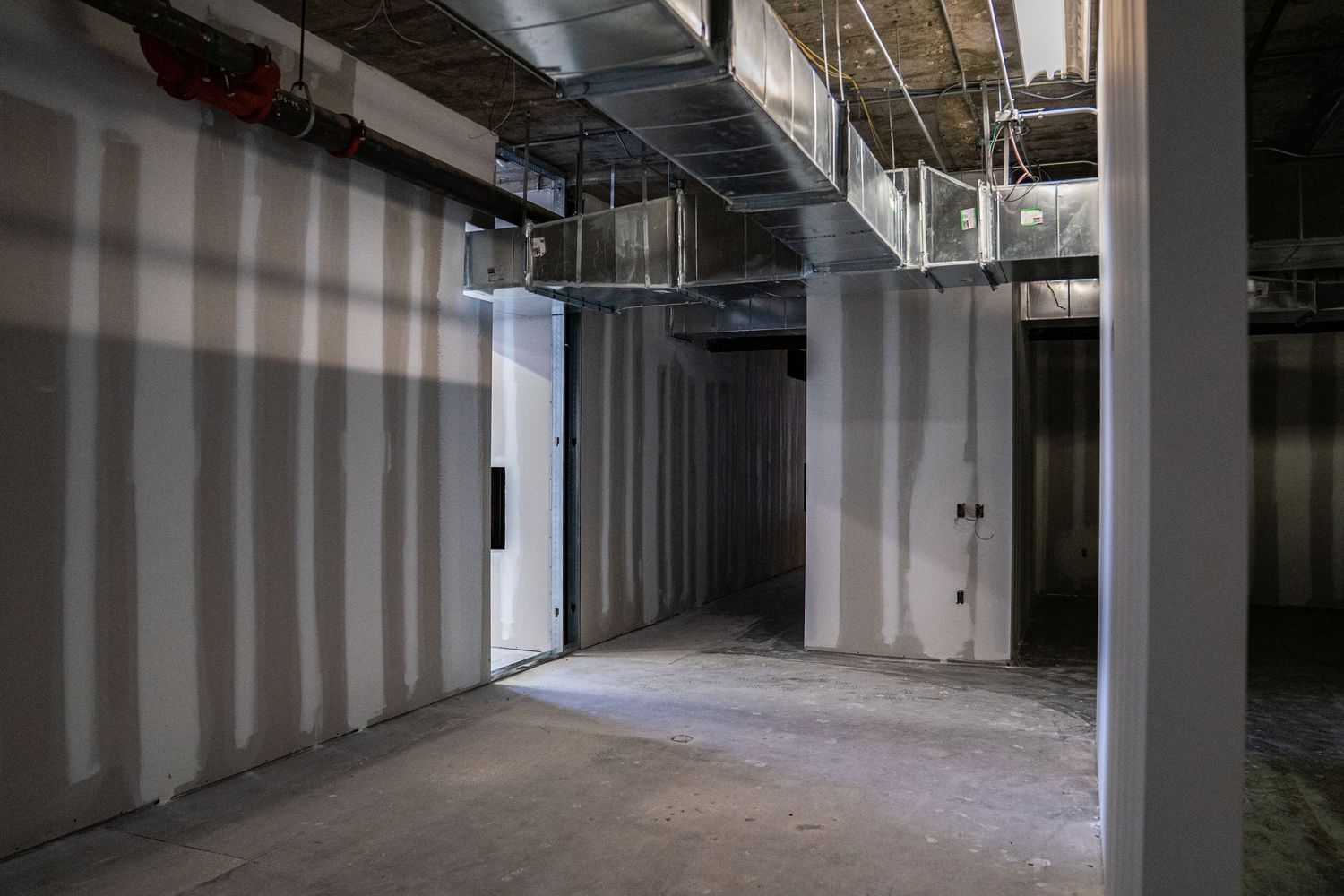 Long view of commercial space showing white walls and support columns during renovation.