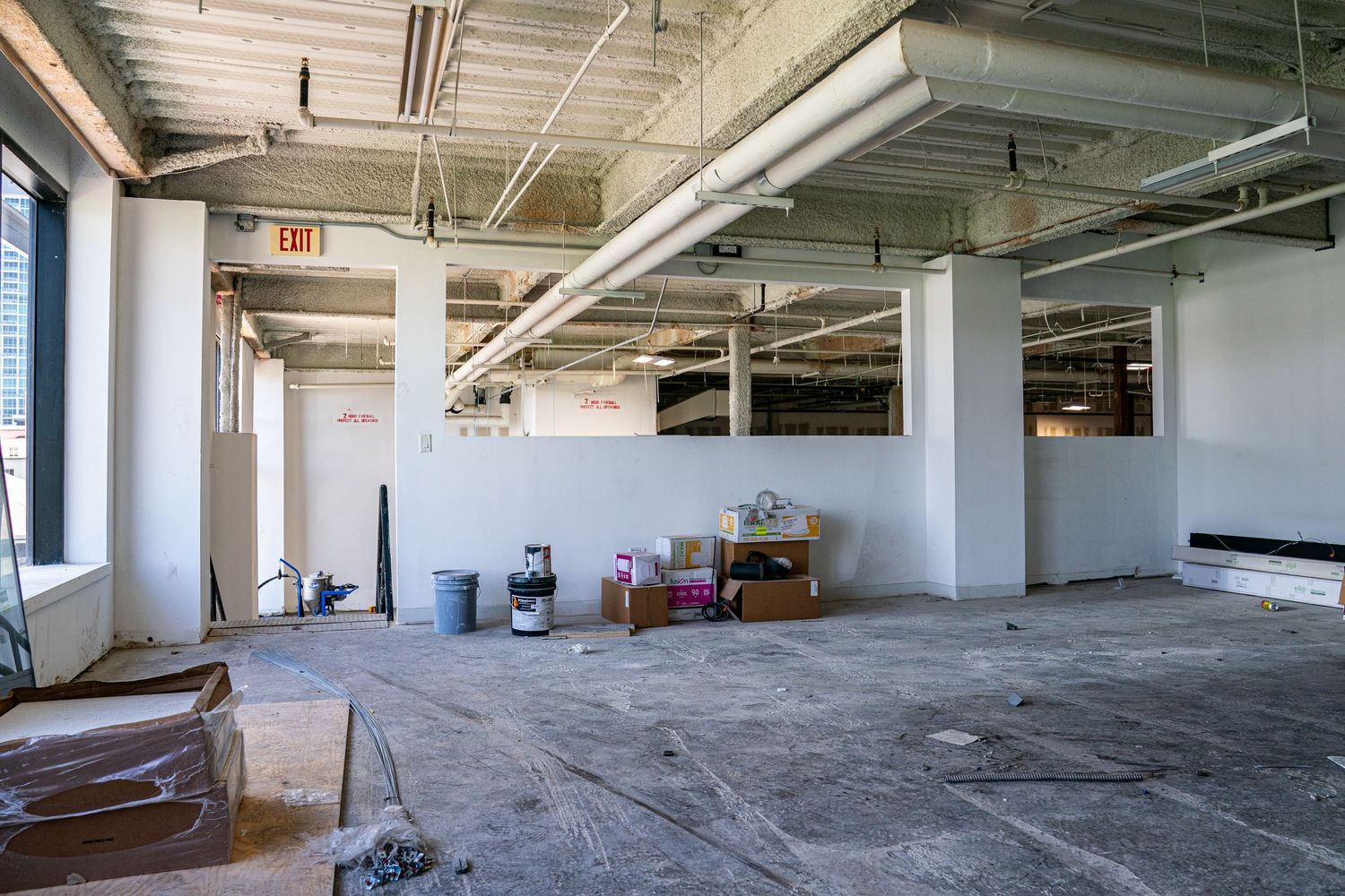 Large empty industrial space with concrete floors and exposed ceiling infrastructure.