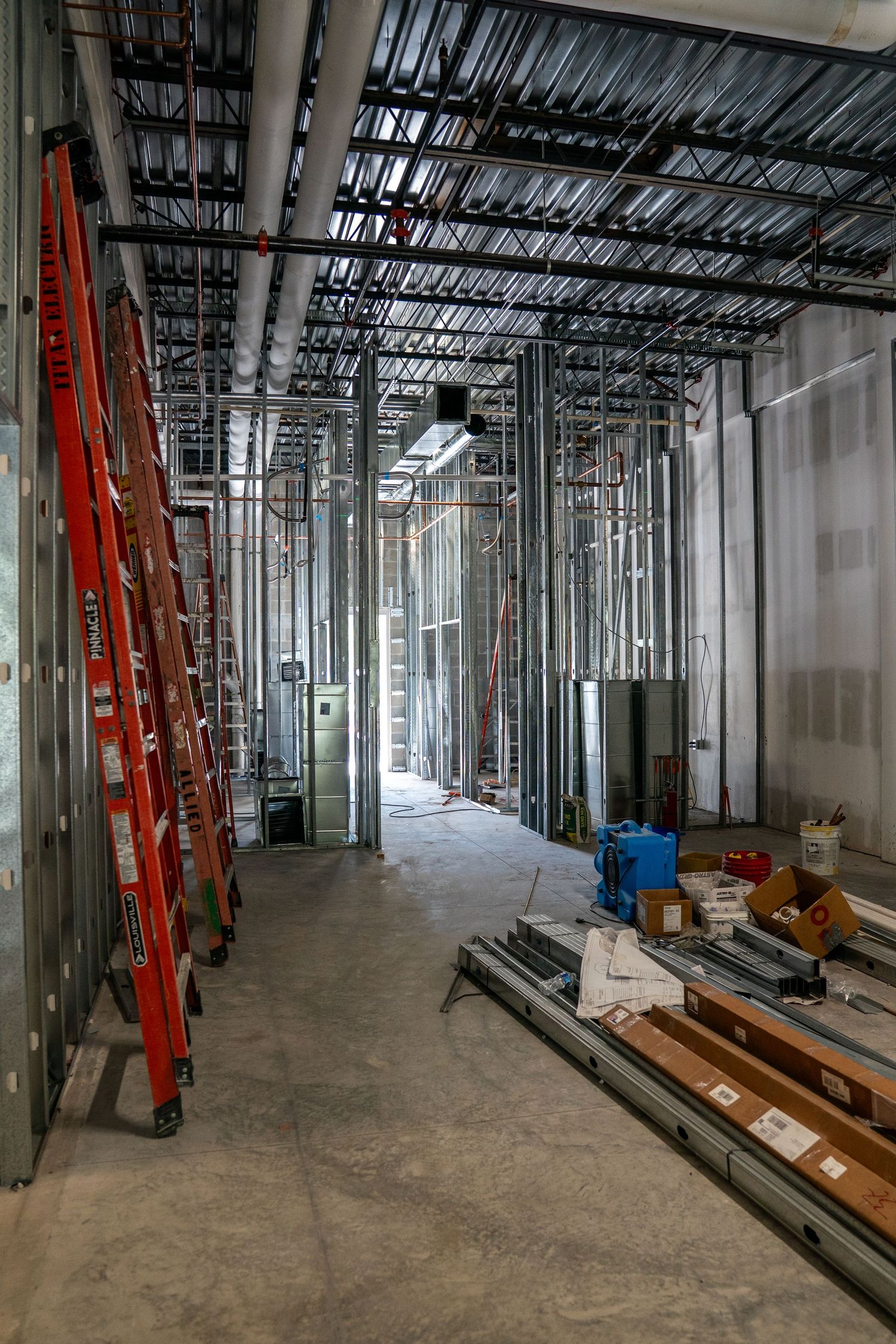 Wide view of commercial construction site with metal framing and scattered building materials.