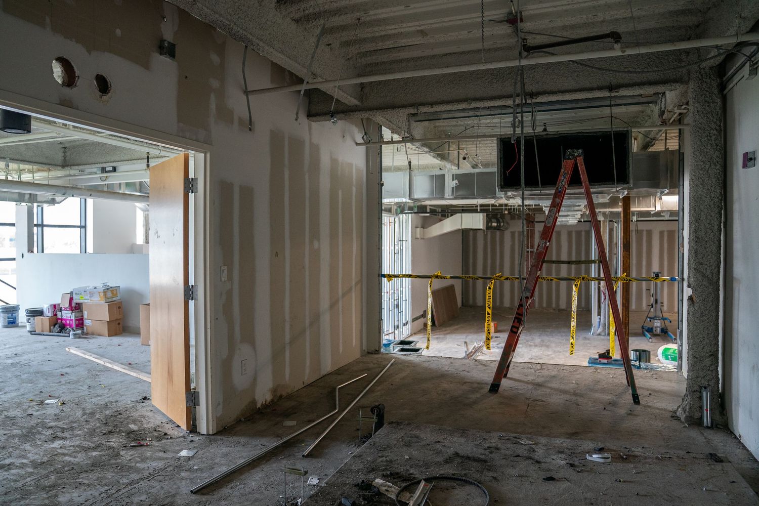 Large empty commercial space under construction with exposed ceiling and concrete floors.