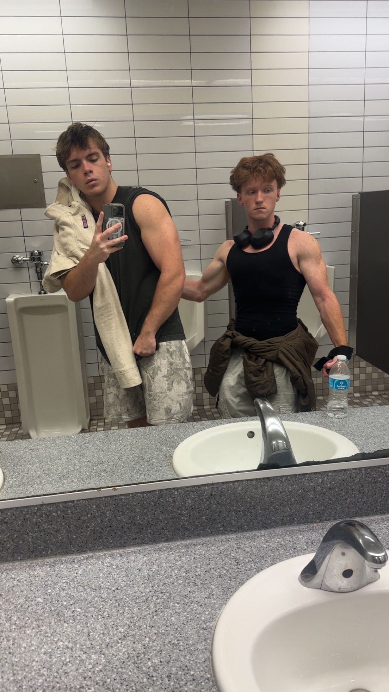 Person in black tank top taking selfies in bathroom mirror while posing in different positions.