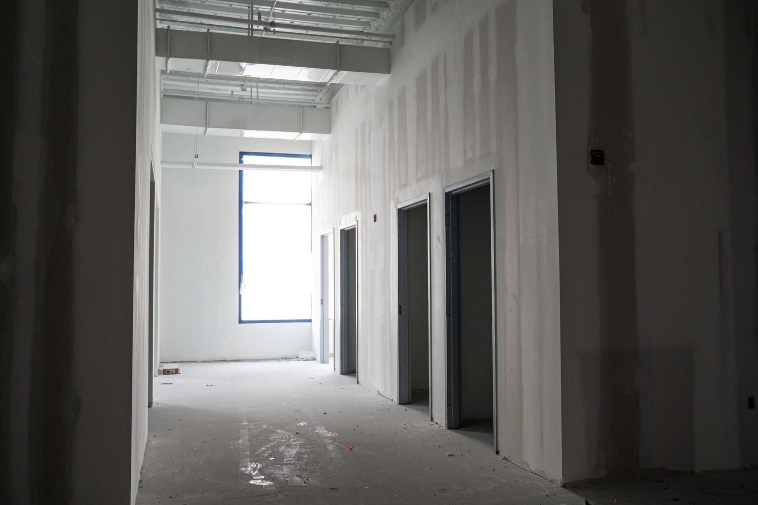 Long corridor view of an empty commercial space under renovation with natural lighting.