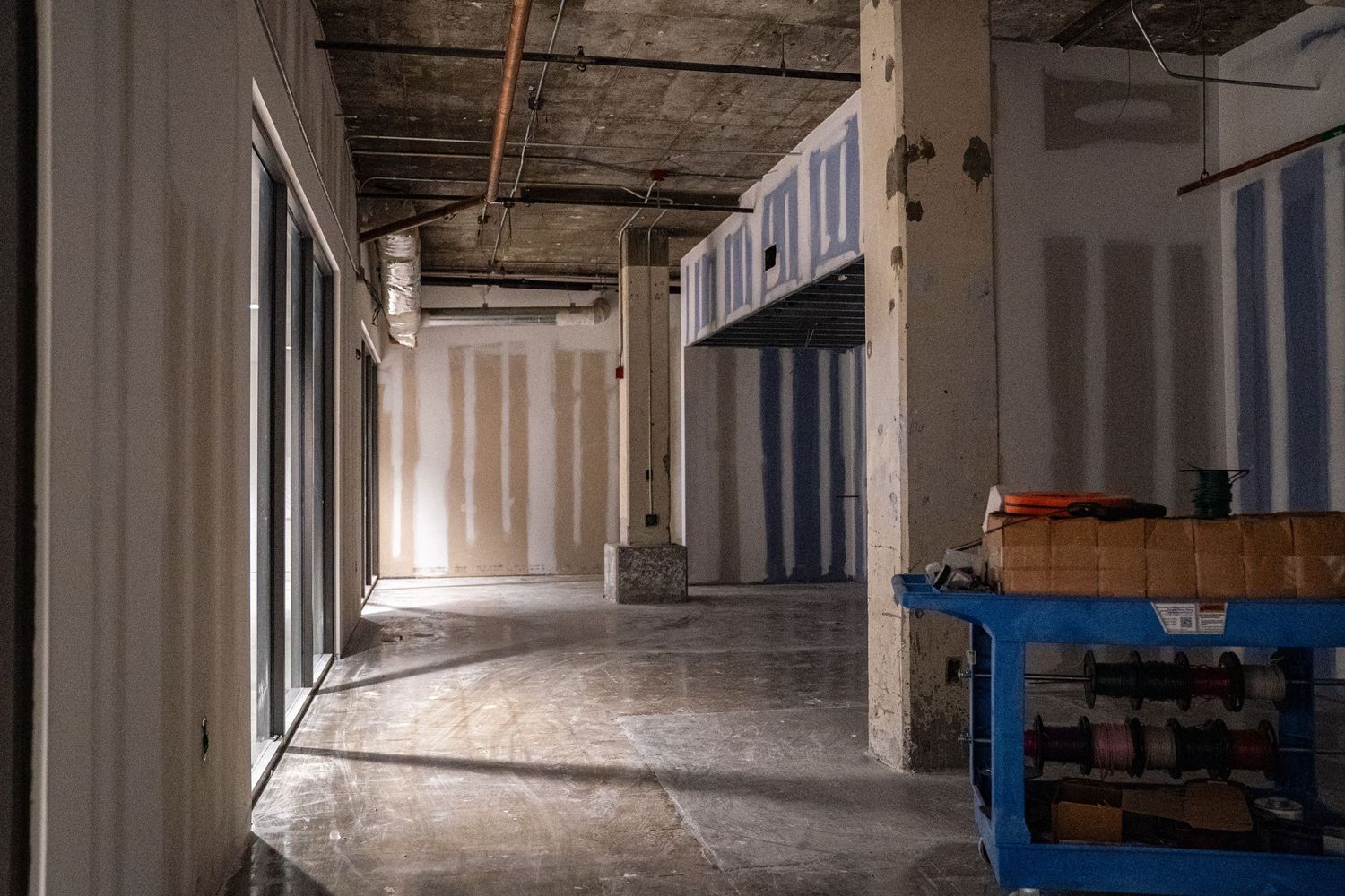 Unfinished commercial interior space with concrete floors and exposed mechanical systems.