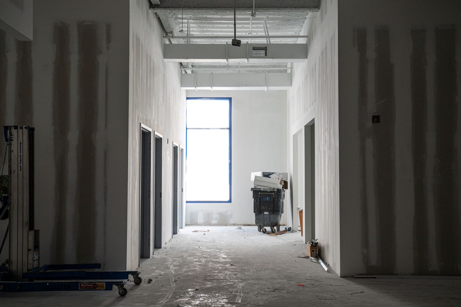 Narrow hallway view of commercial construction project with metal framing and drywall.