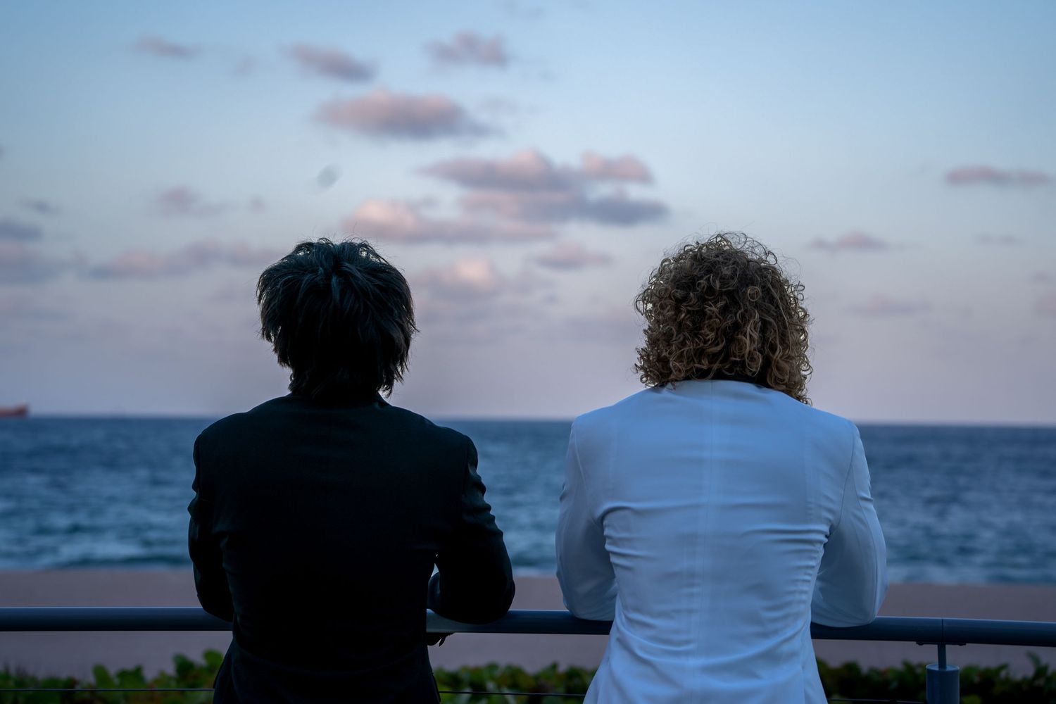 Couple silhouetted against sunset sky and ocean view.