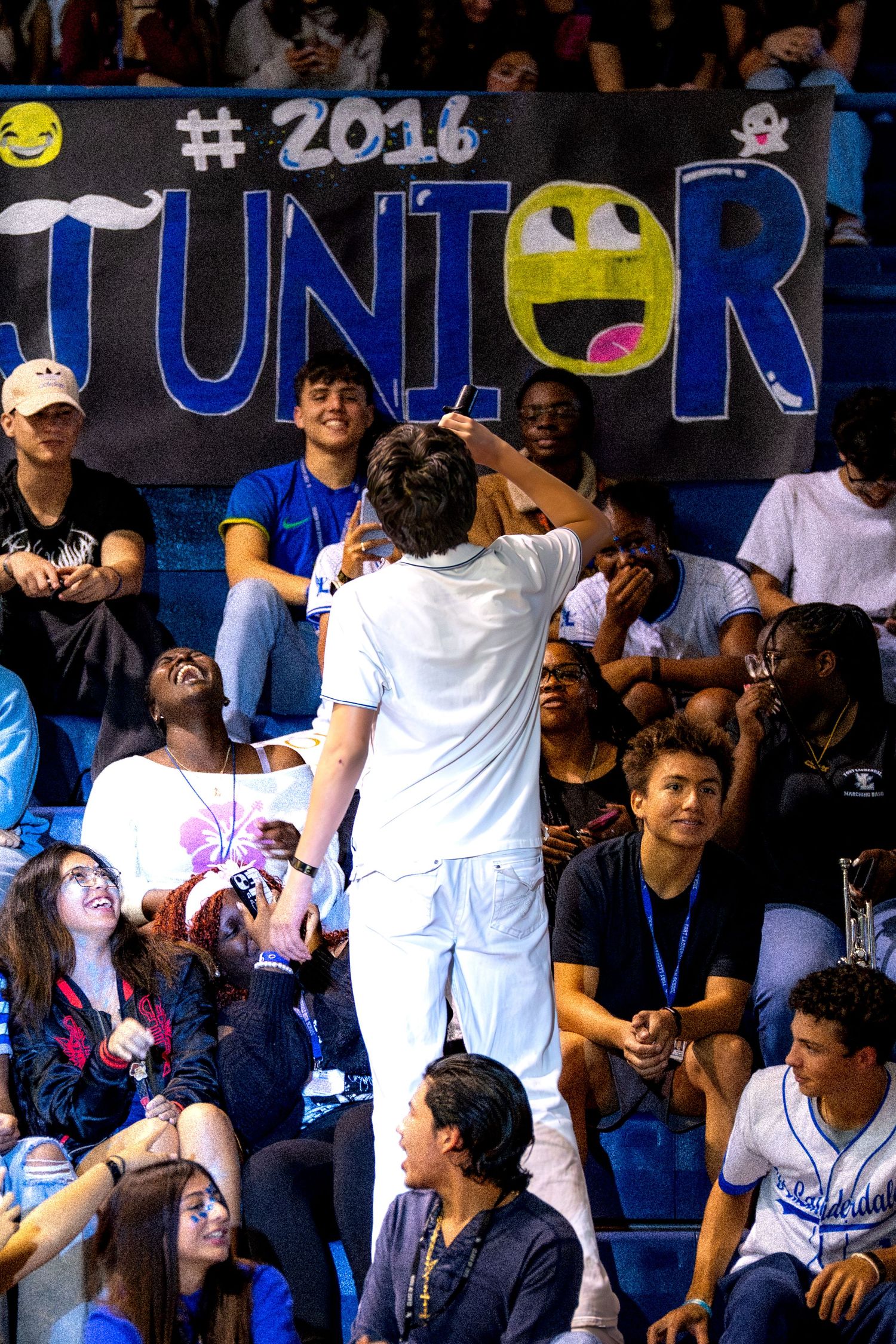 High school juniors celebrate in the bleachers in front of a 2016 Junior class banner during a school pep rally.
