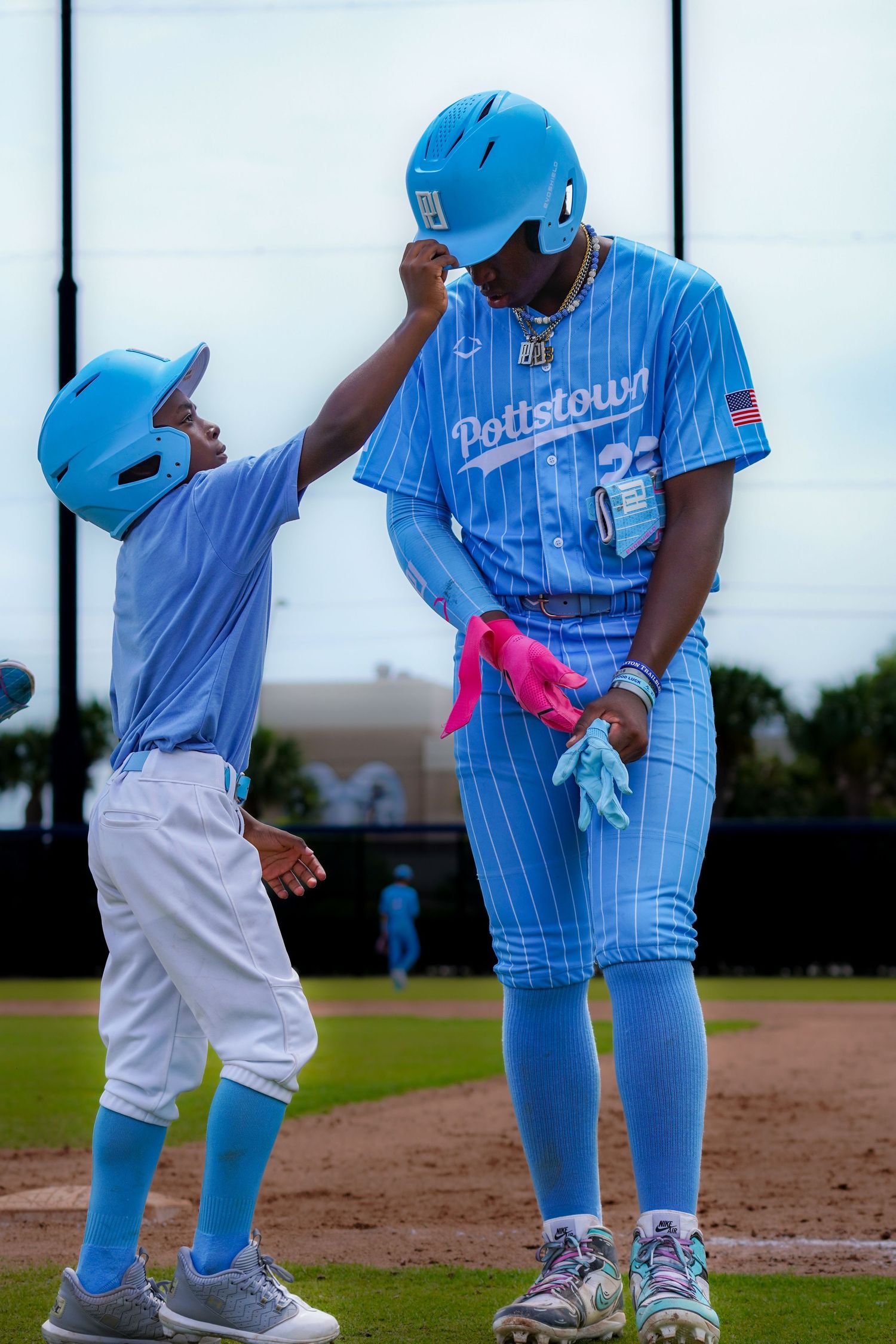 Baseball players in light blue pinstripe uniforms practicing fielding drills.