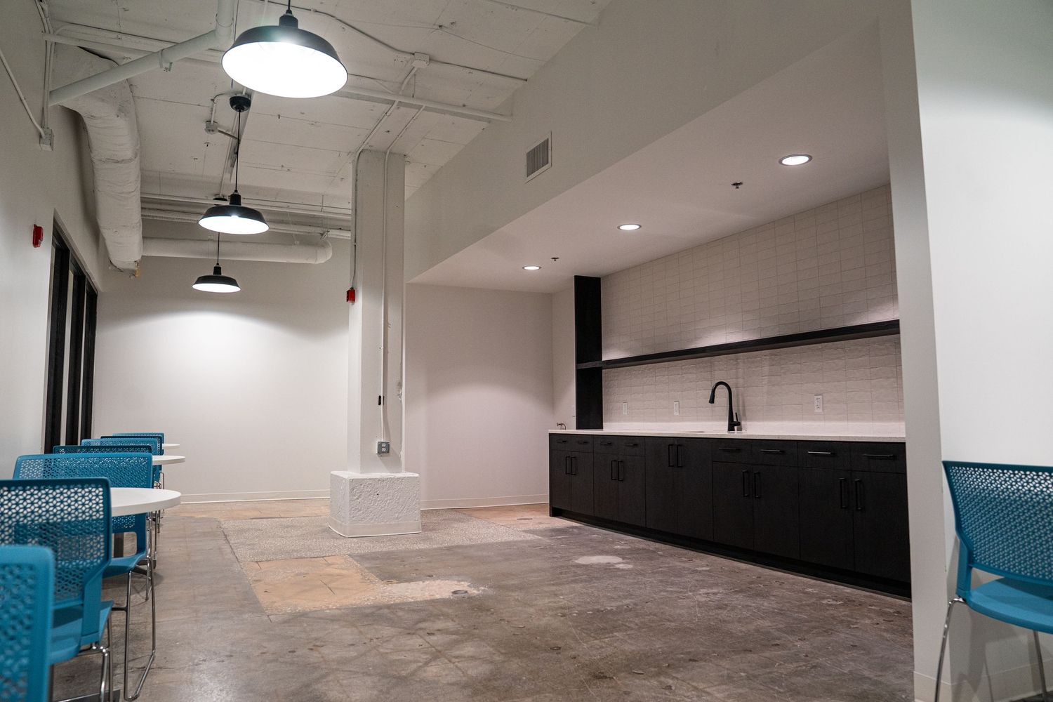 Industrial style office space with exposed ceiling systems and modern pendant lighting fixtures.