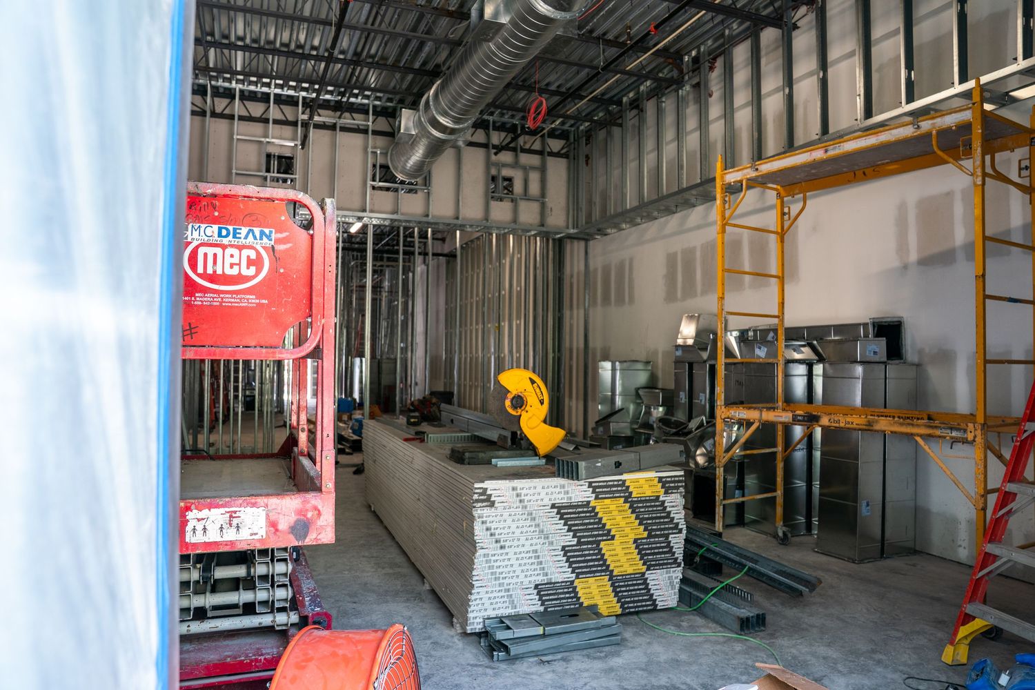 Construction site interior with scaffolding and building materials staged along walls.