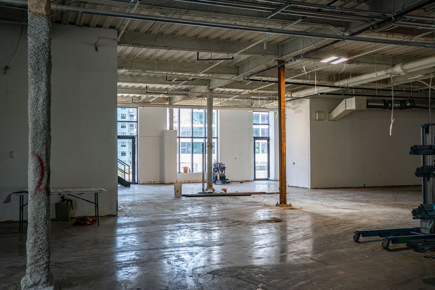 Large open commercial space with concrete floors and floor-to-ceiling windows.