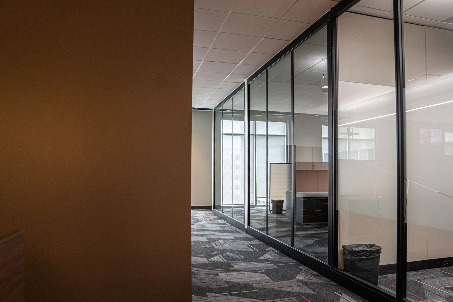 Panoramic view of an unfinished office interior with glass walls and industrial ceiling.