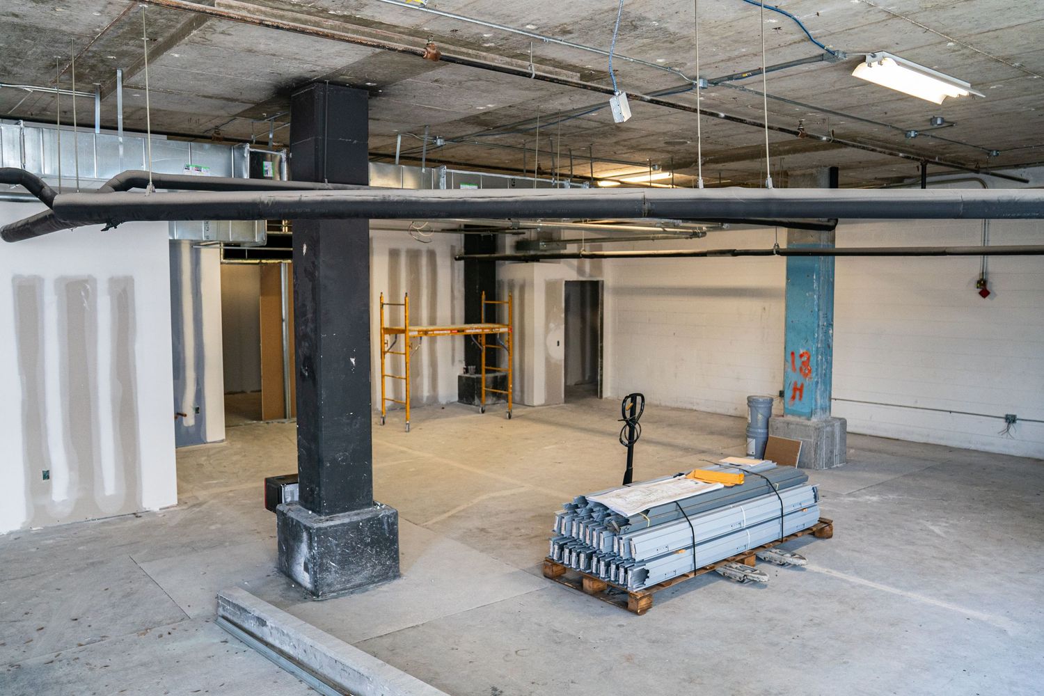 Large empty industrial space with exposed ductwork and concrete pillars.