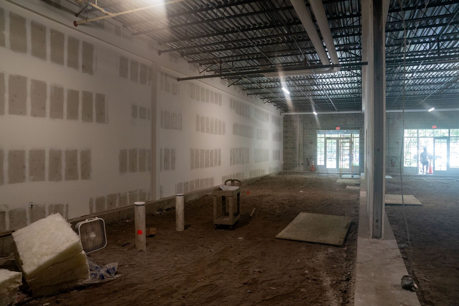 Interior of unfinished commercial space with exposed drywall, concrete floor, and industrial ceiling.