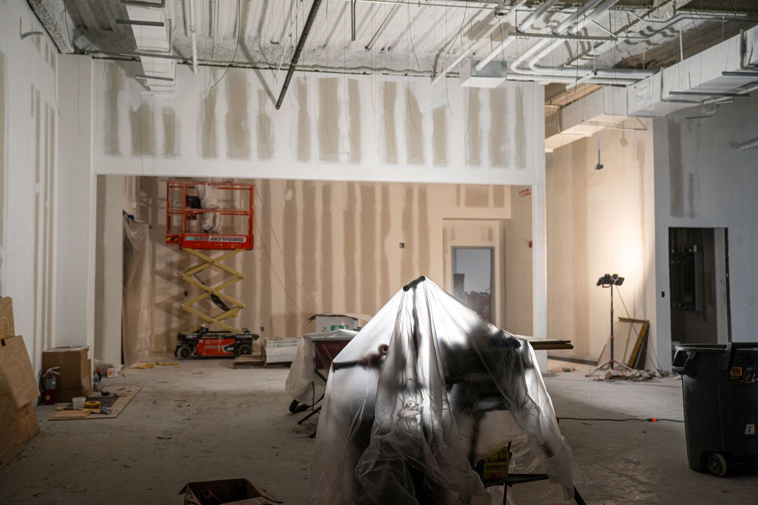 Panoramic view of commercial construction site with drywall installation in progress.