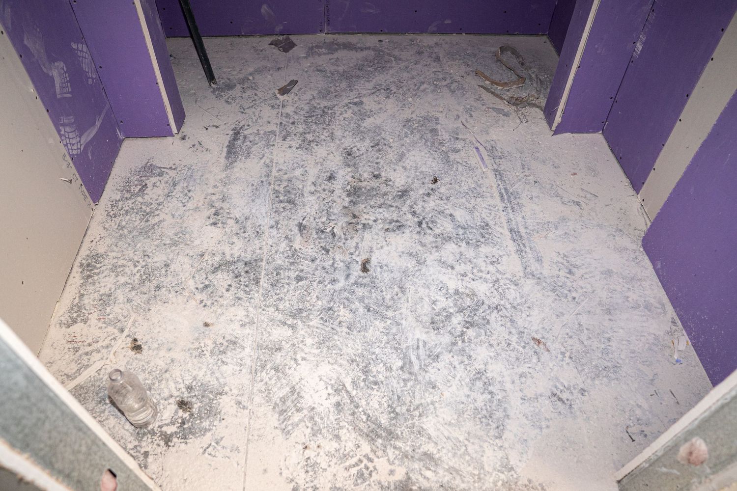 Unfinished commercial space with purple walls and exposed ceiling during renovation.