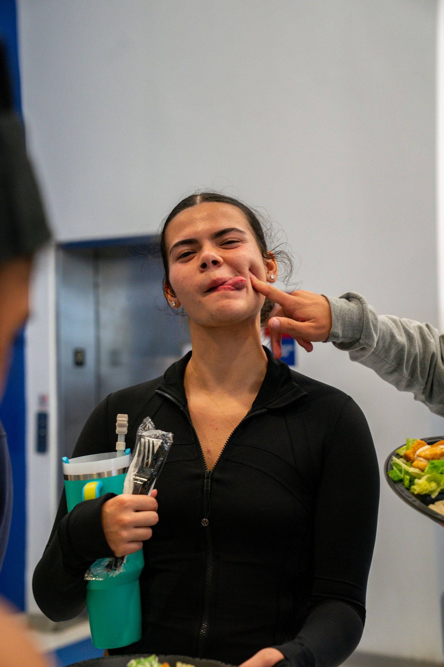 Person in black jacket enjoying food and making expressions.