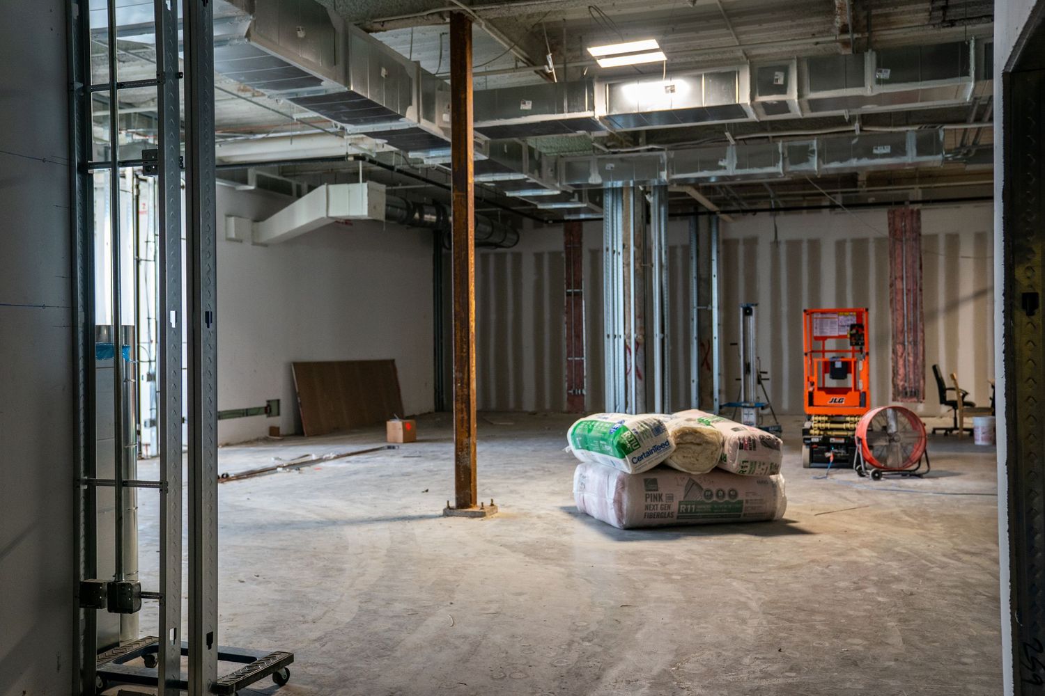 Large empty commercial space under construction with exposed ceiling and concrete floors.