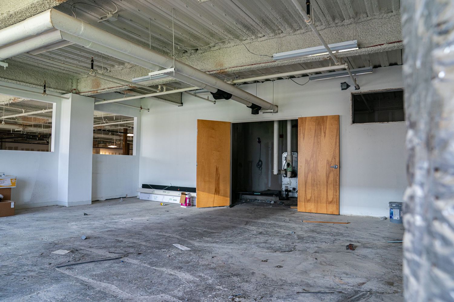 Unfinished commercial interior with concrete floors and exposed mechanical systems.