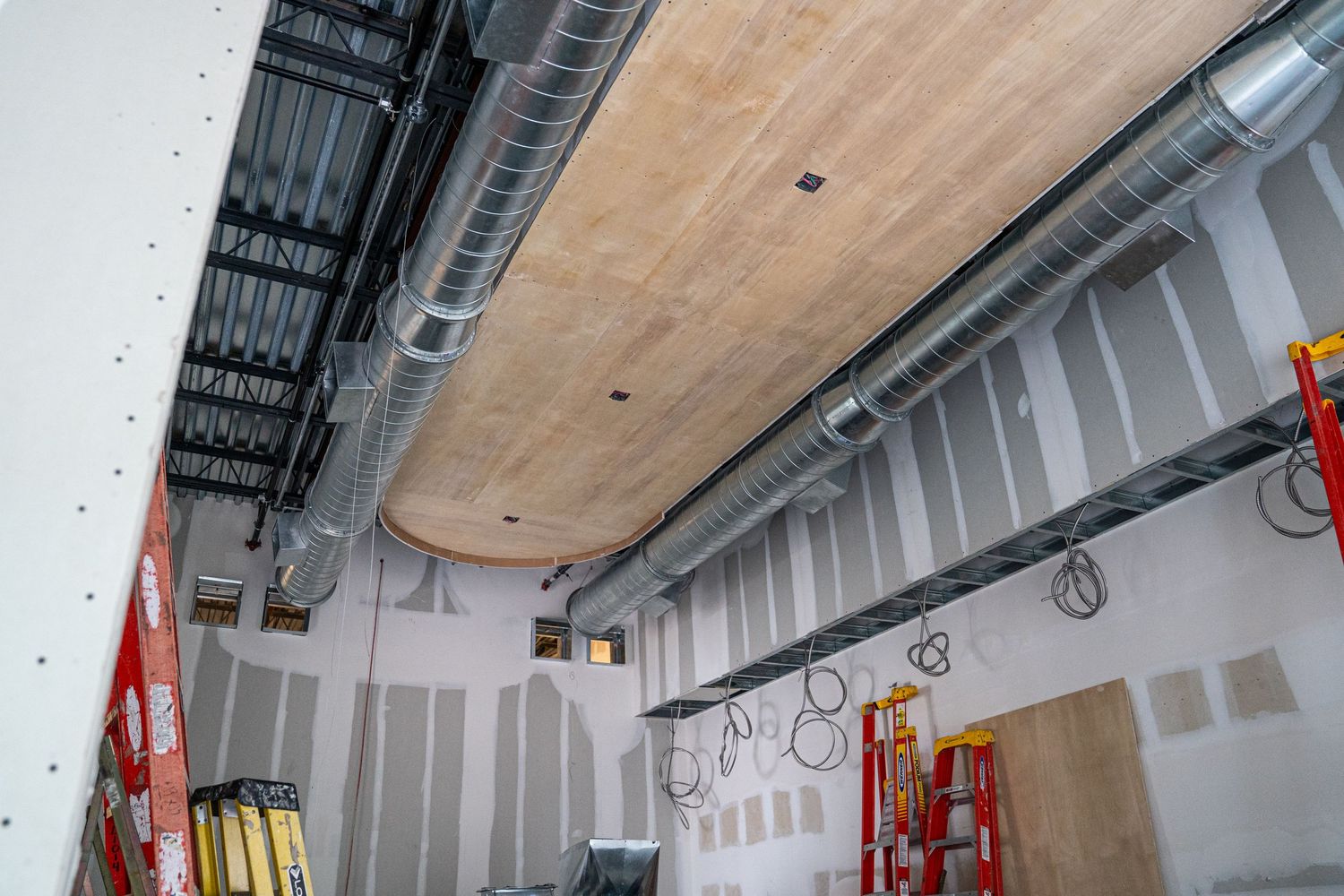 Interior renovation space with metal studs and wooden ceiling panels being installed.