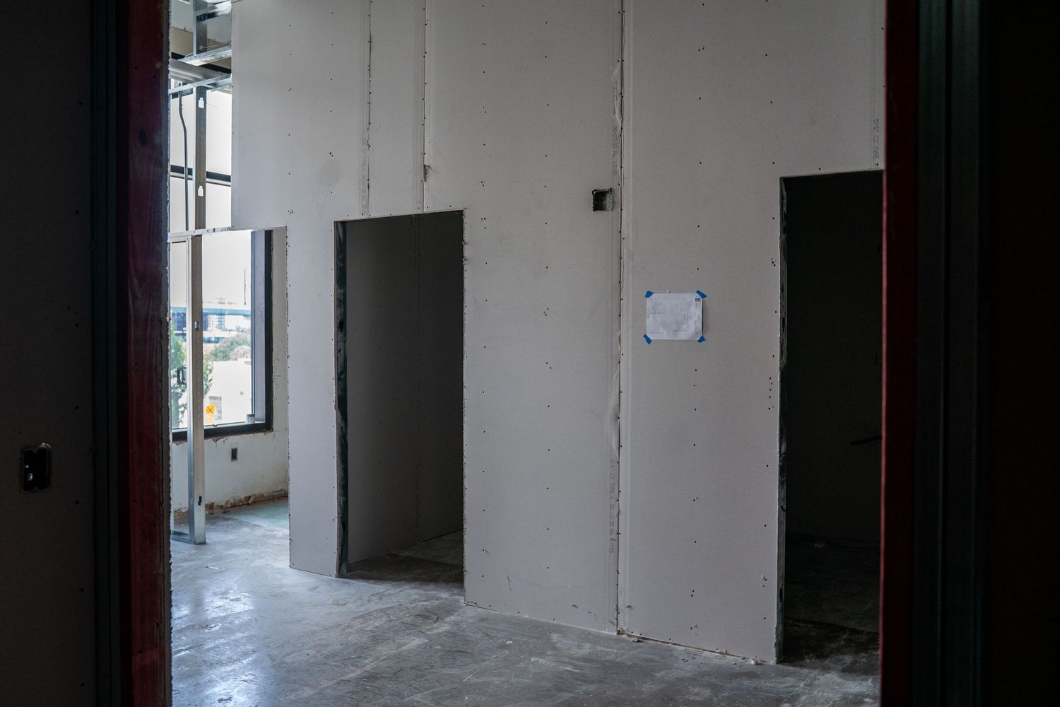 Dark hallway showing unfinished doorways and bare walls during construction phase.