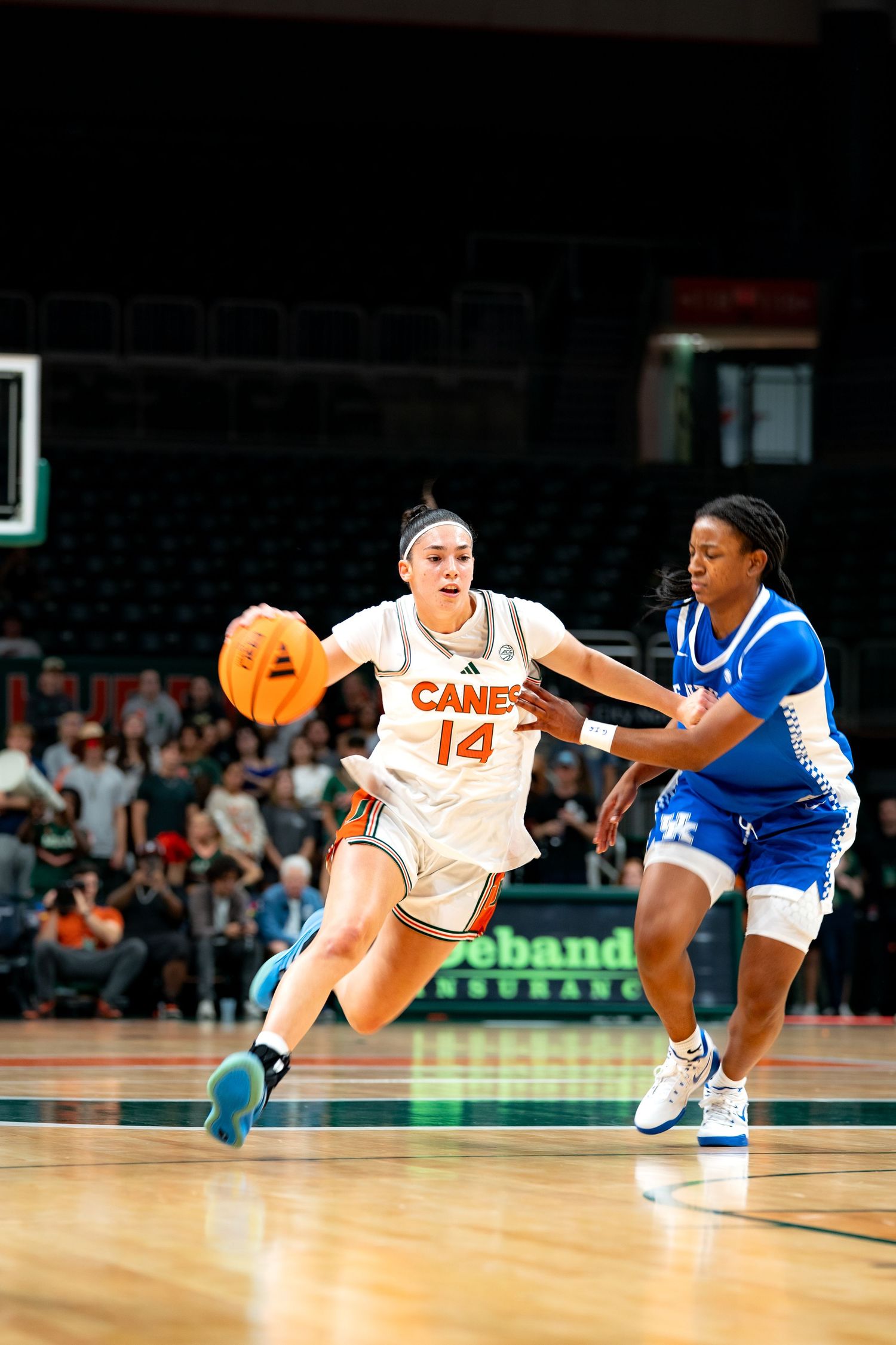 Basketball players diving for loose ball during intense game action.