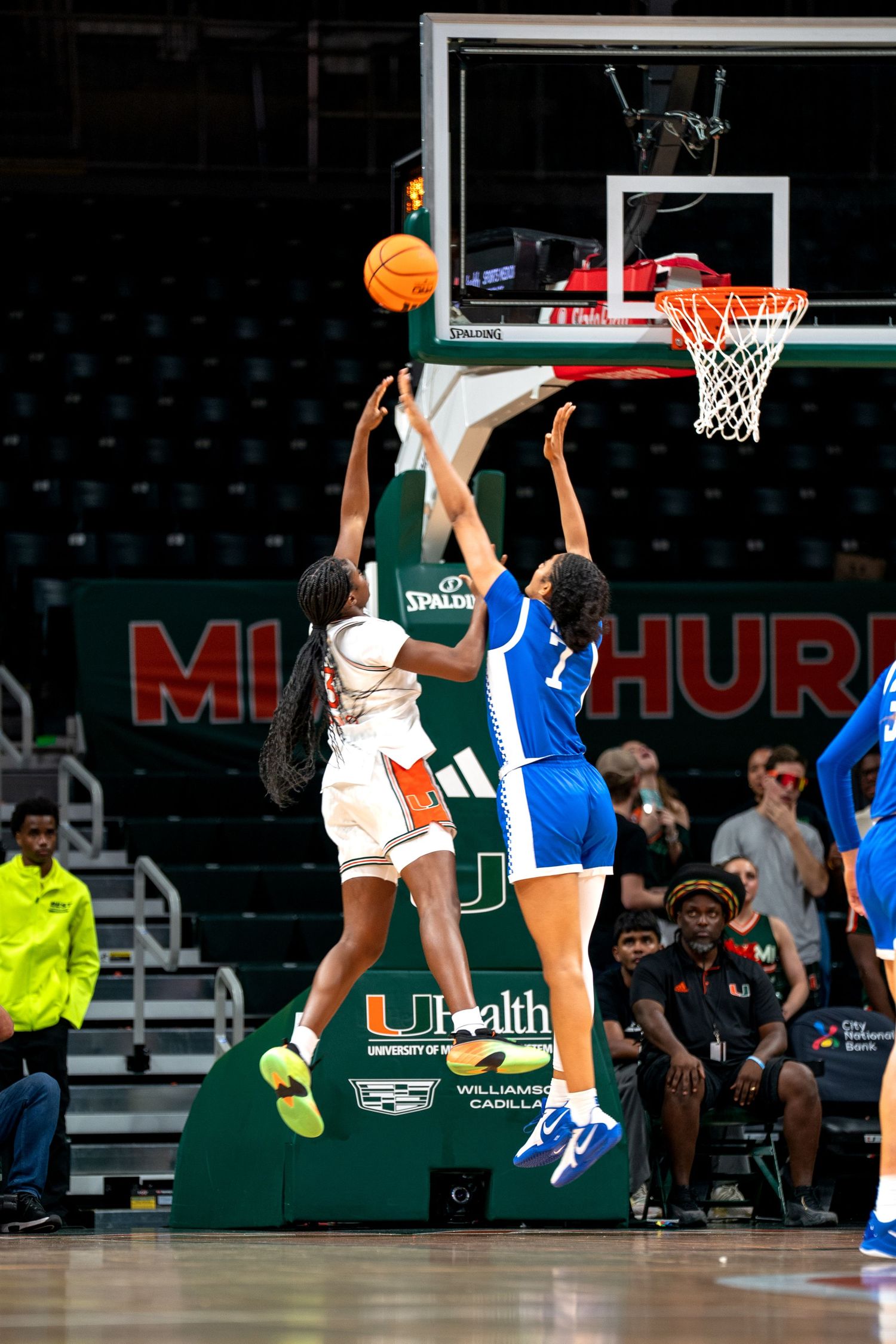 Basketball players jumping for the ball during a game at an indoor arena.